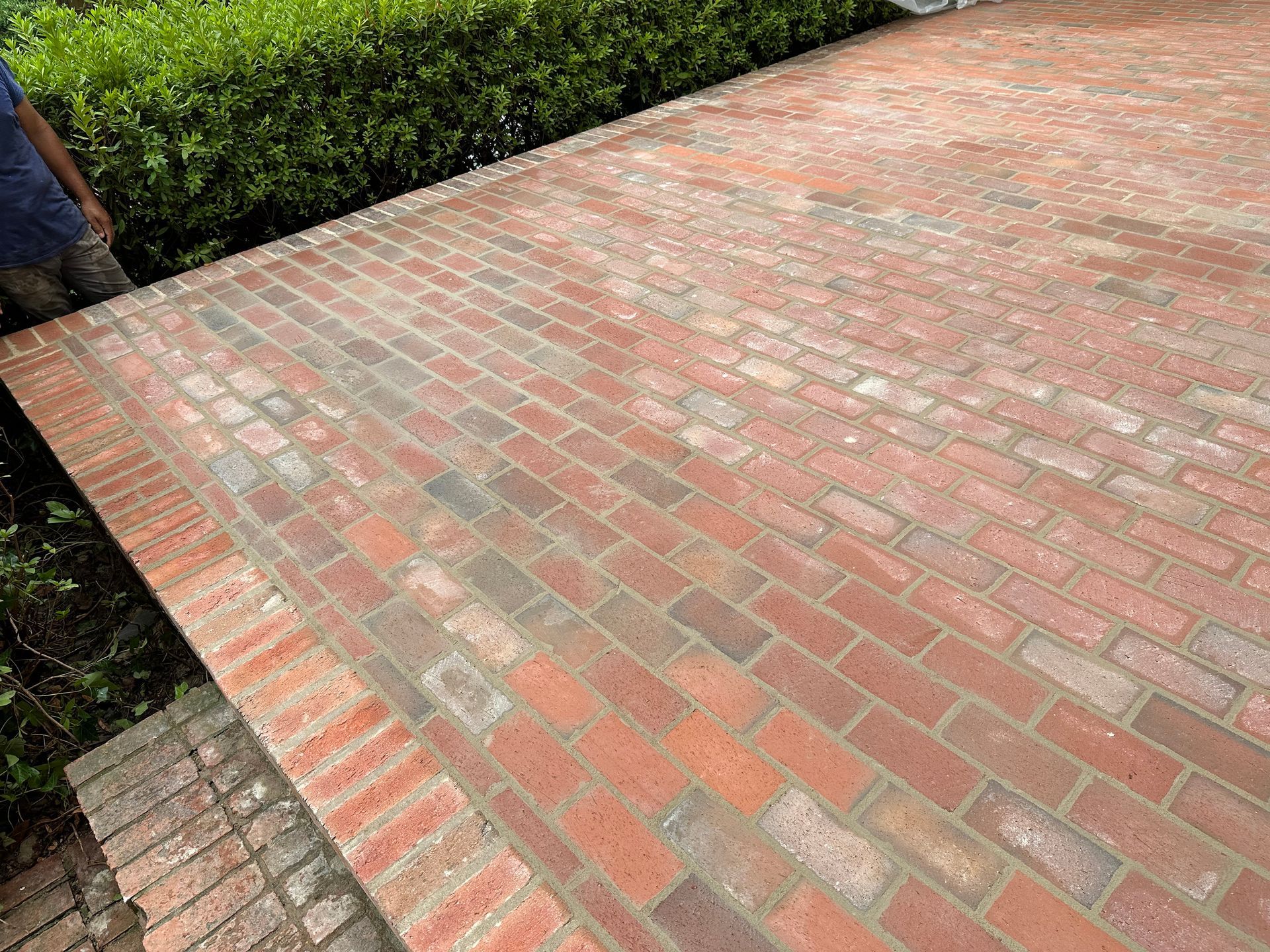 A man is standing next to a brick driveway.