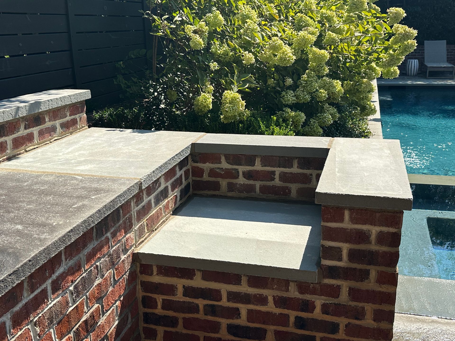 A brick wall sits next to a swimming pool