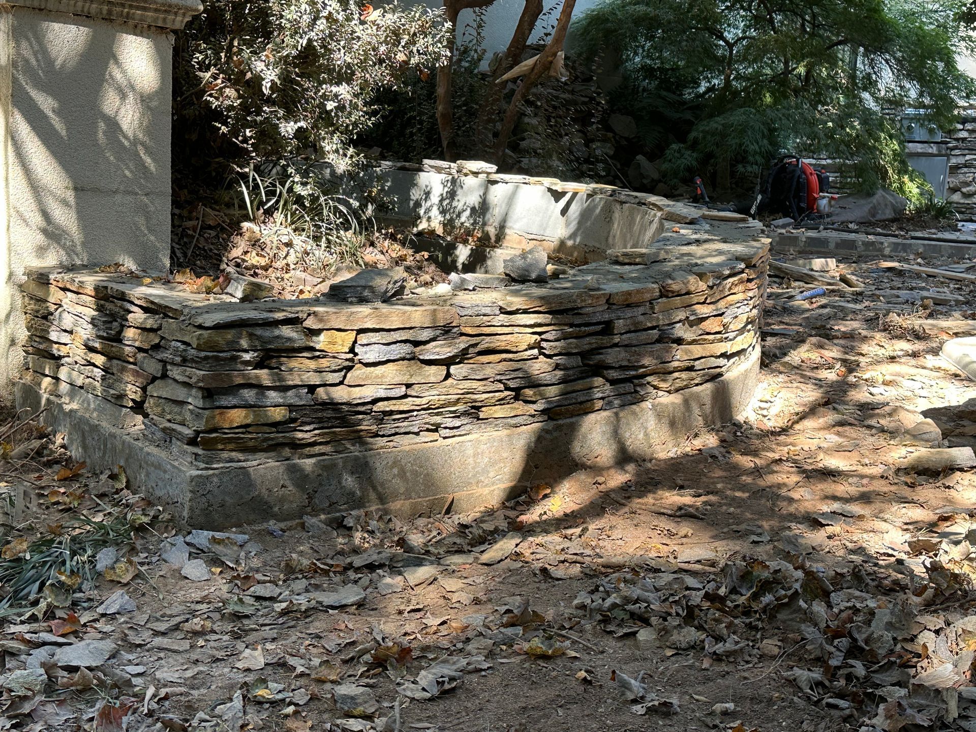 A stone wall is being built in the middle of a dirt field.
