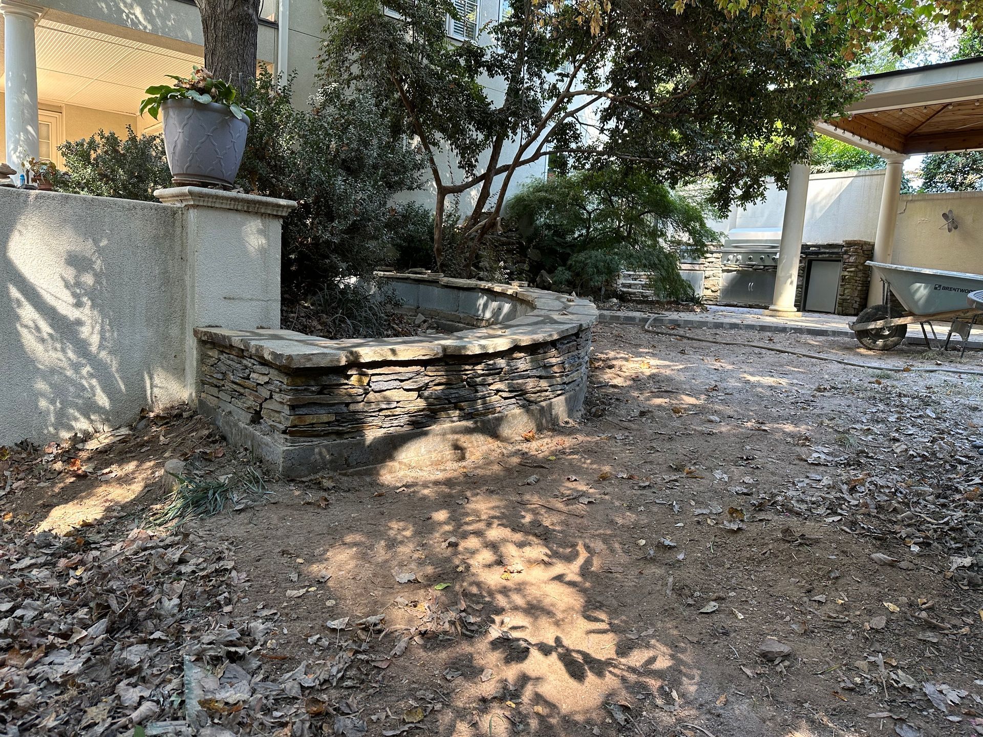 A stone bench is sitting in the dirt in front of a house.