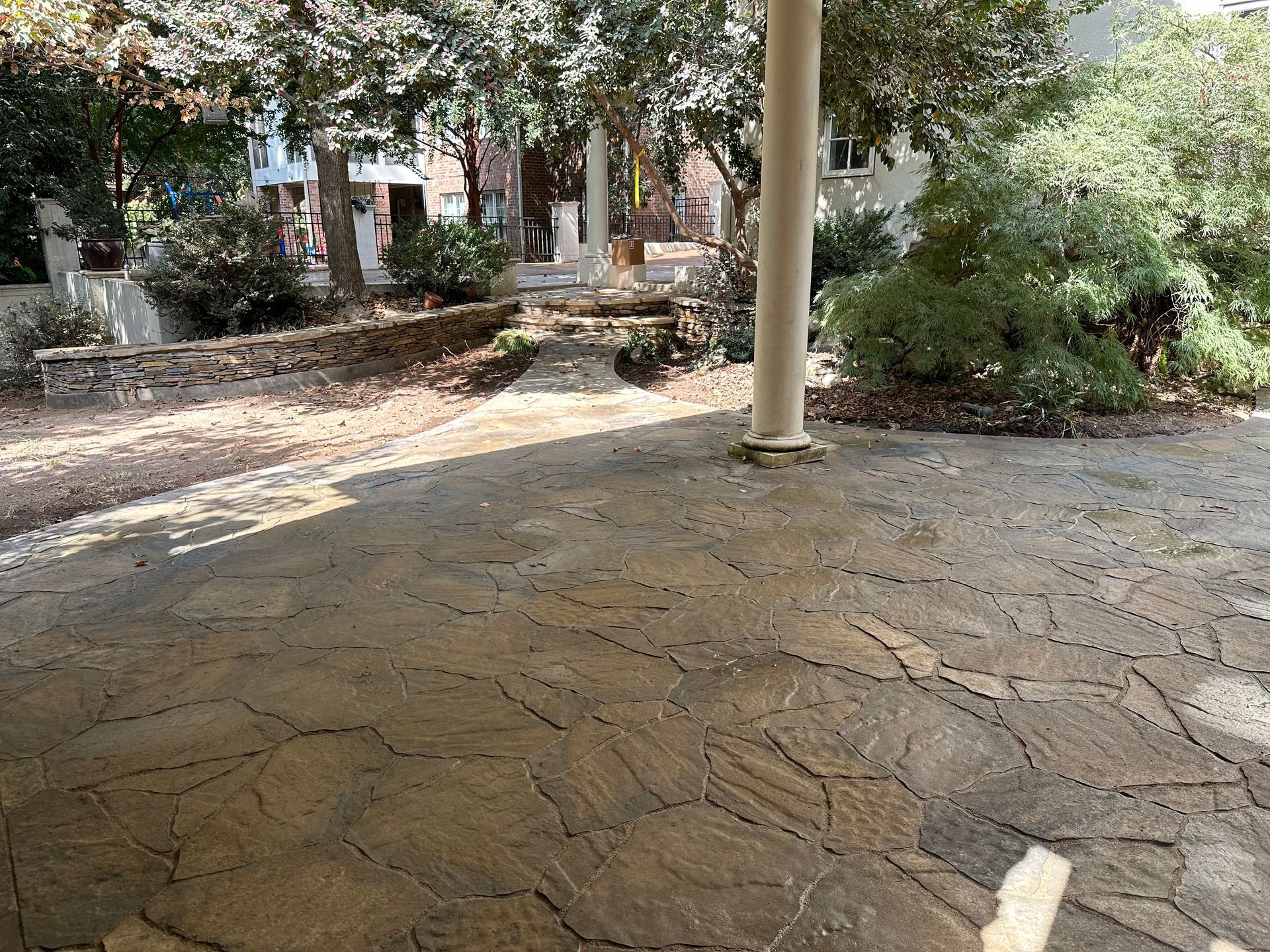 A patio with a pillar and trees in the background