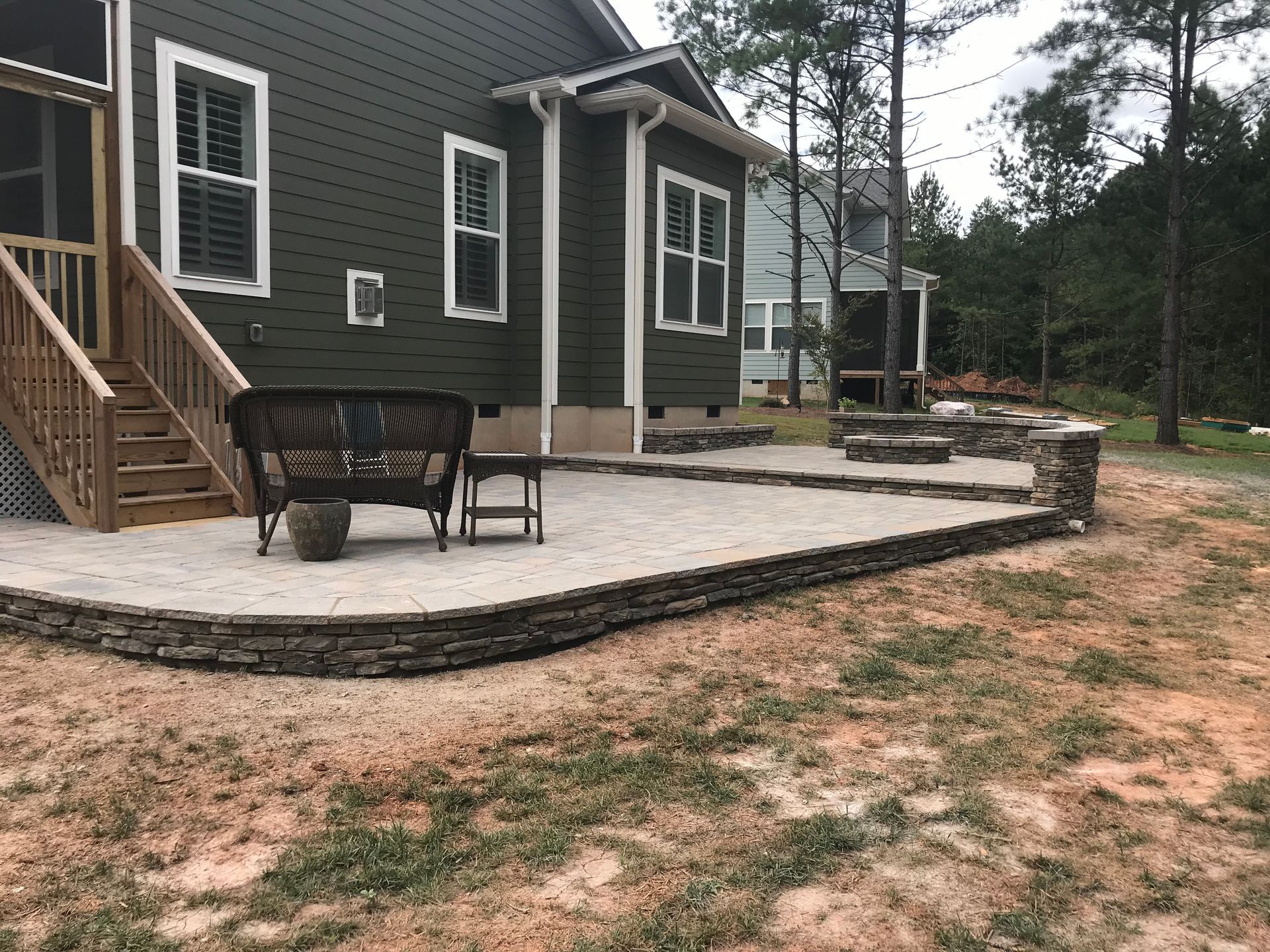 A green house with a patio in front of it.