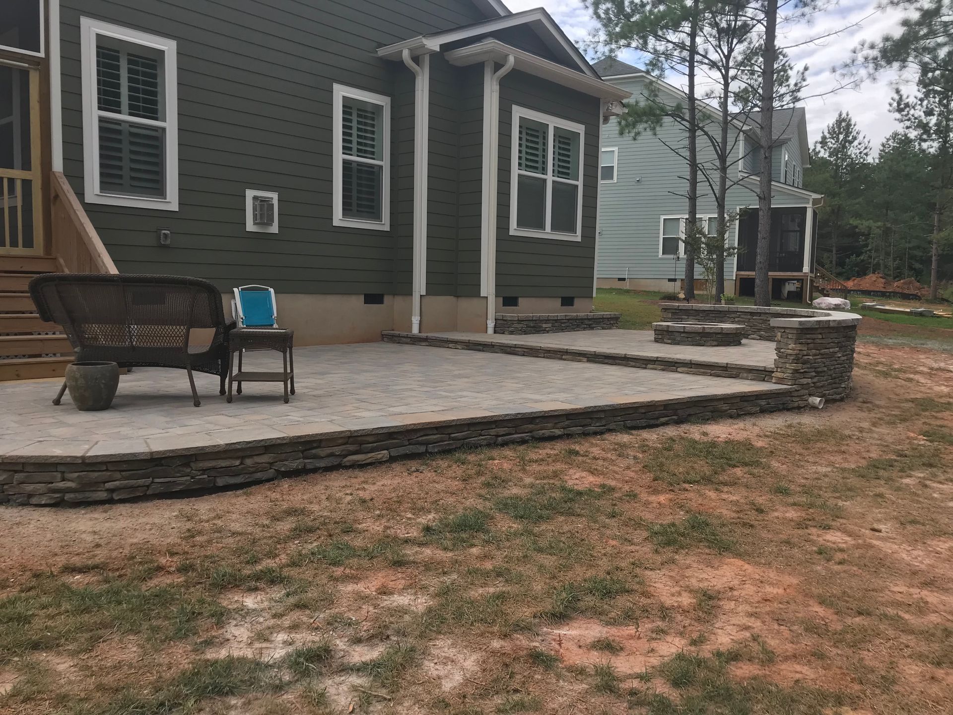 A patio with a bench and chairs in front of a house.