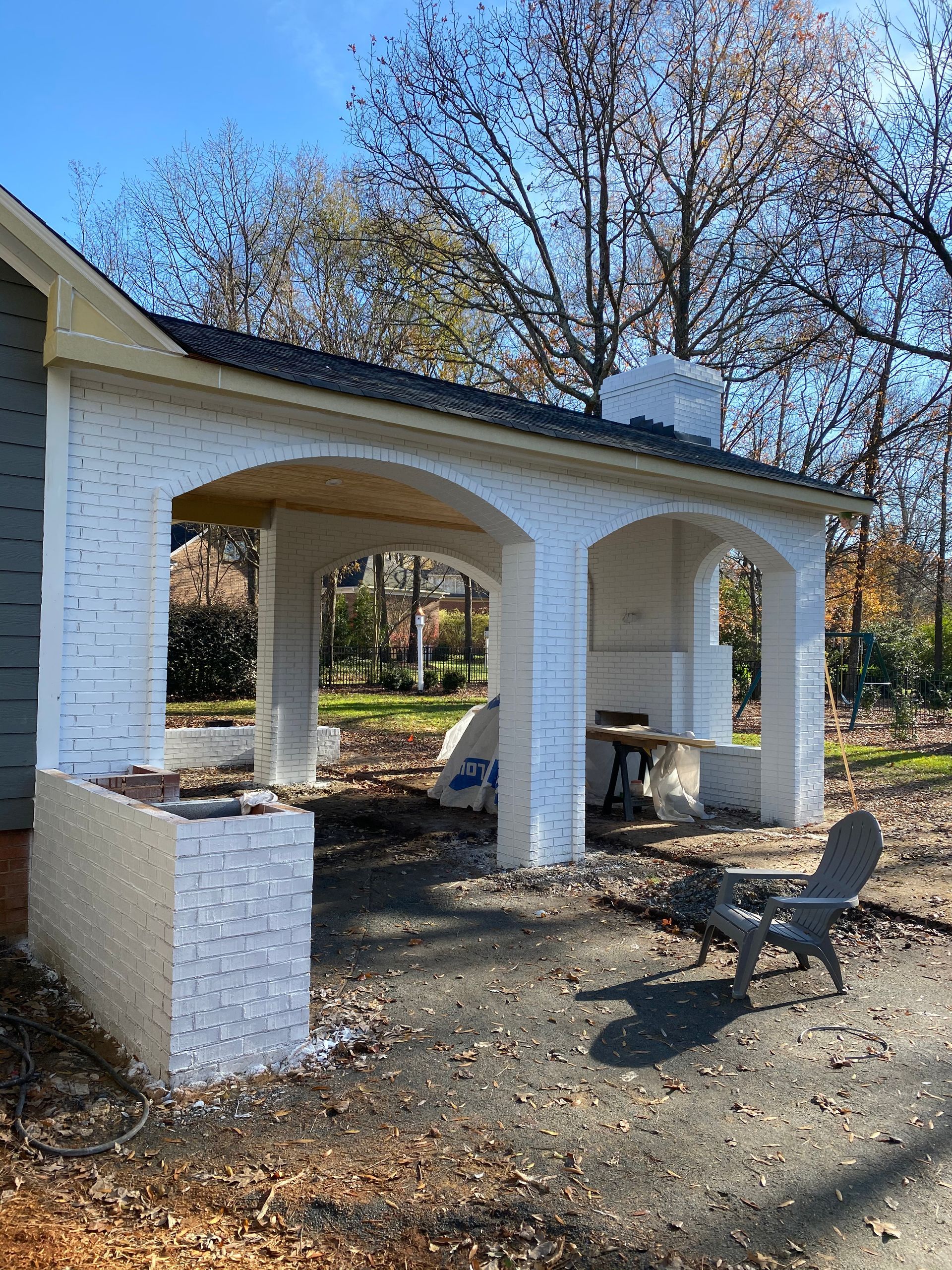 A white brick pavilion is being built in the backyard of a house.