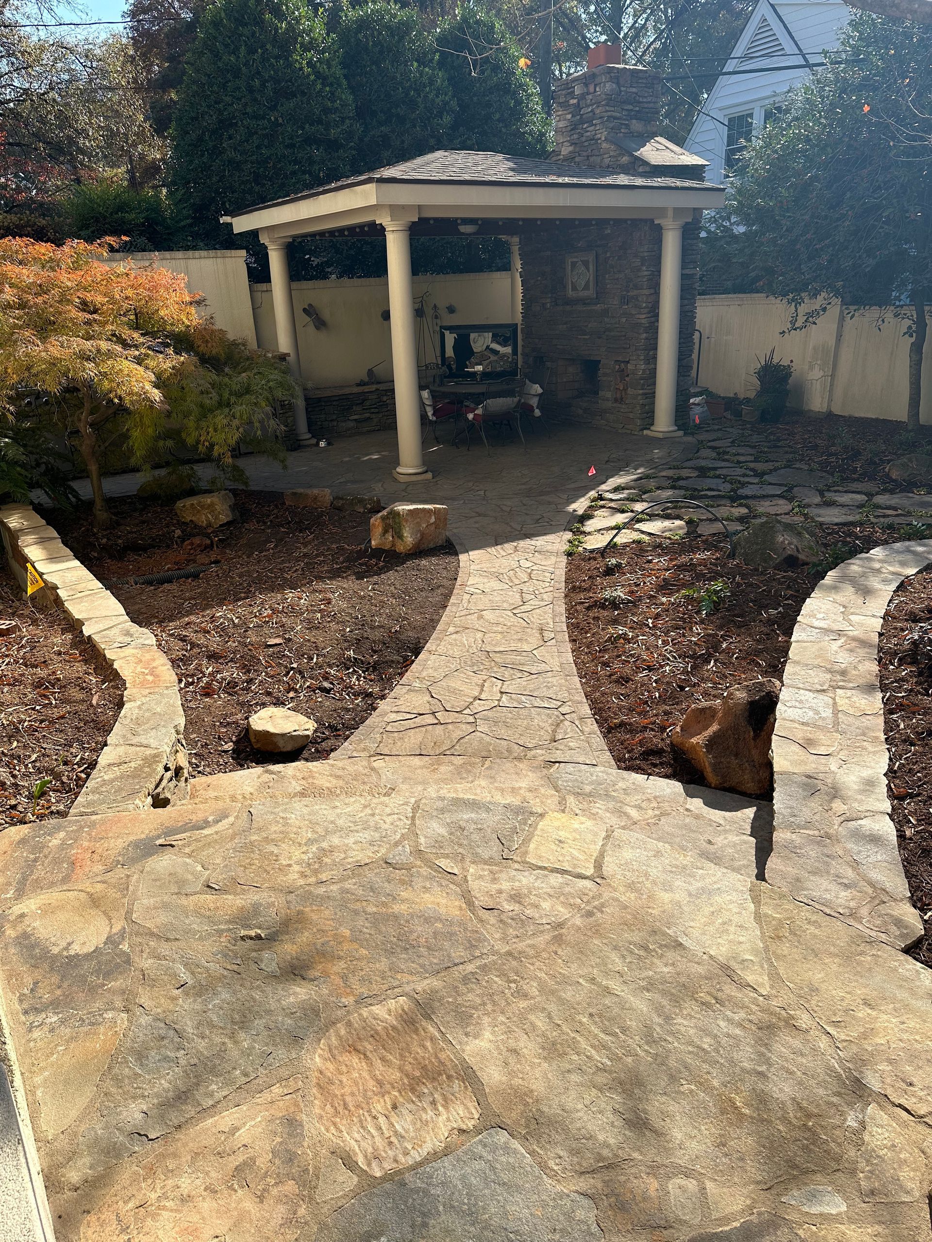 A stone walkway leading to a gazebo in a backyard.