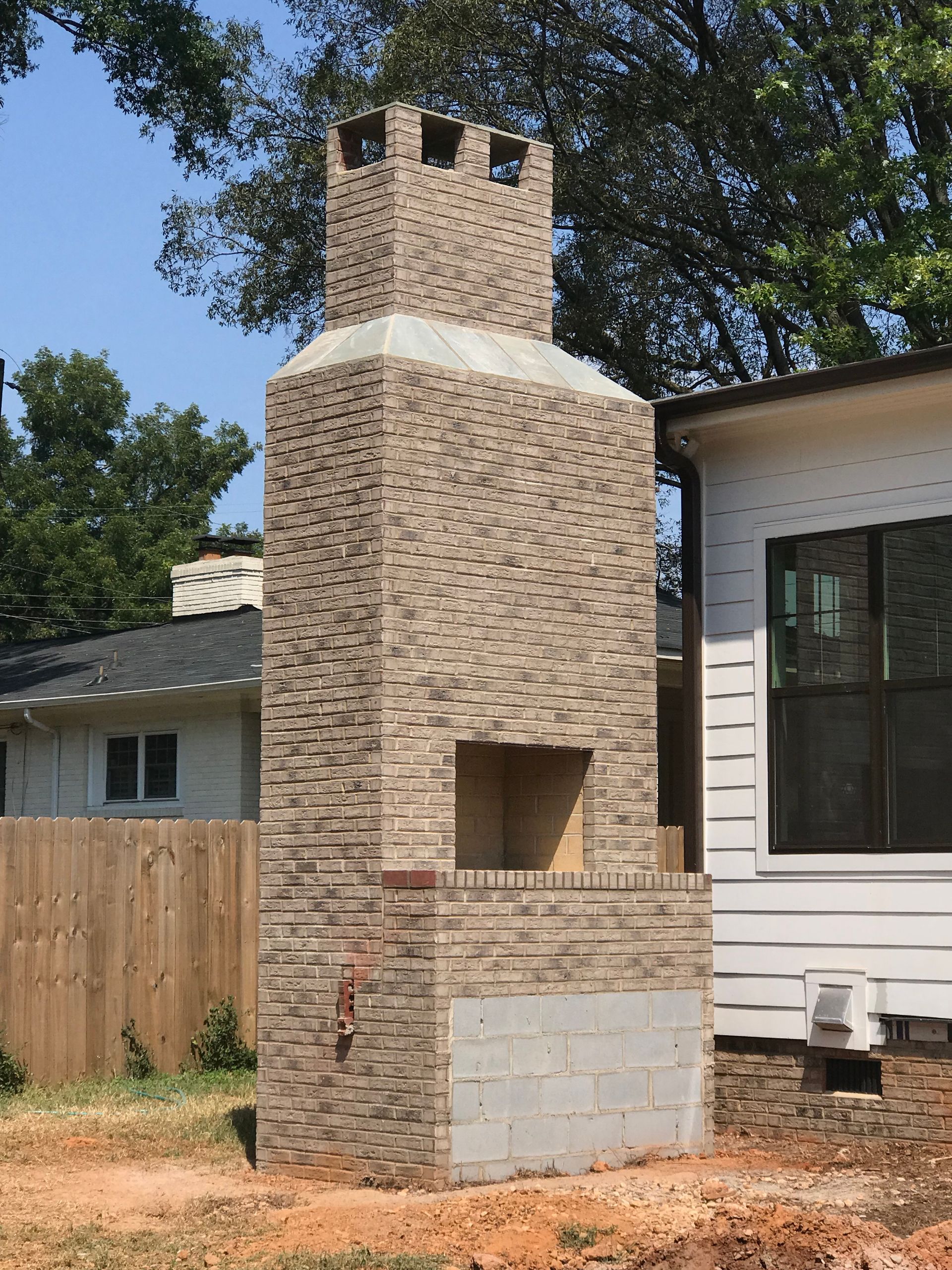 A large brick chimney is in the backyard of a house