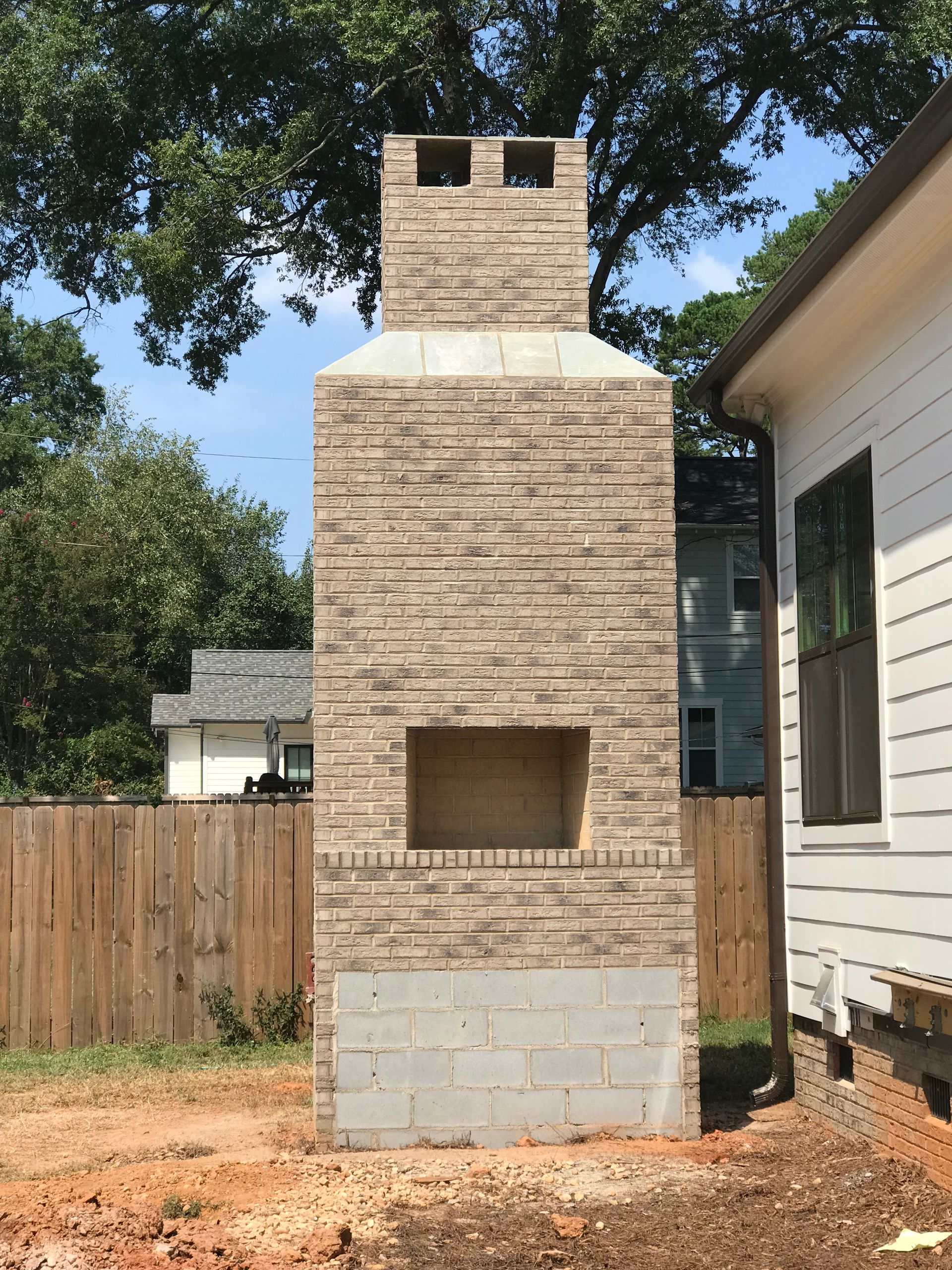 A large brick fireplace is in the backyard of a house