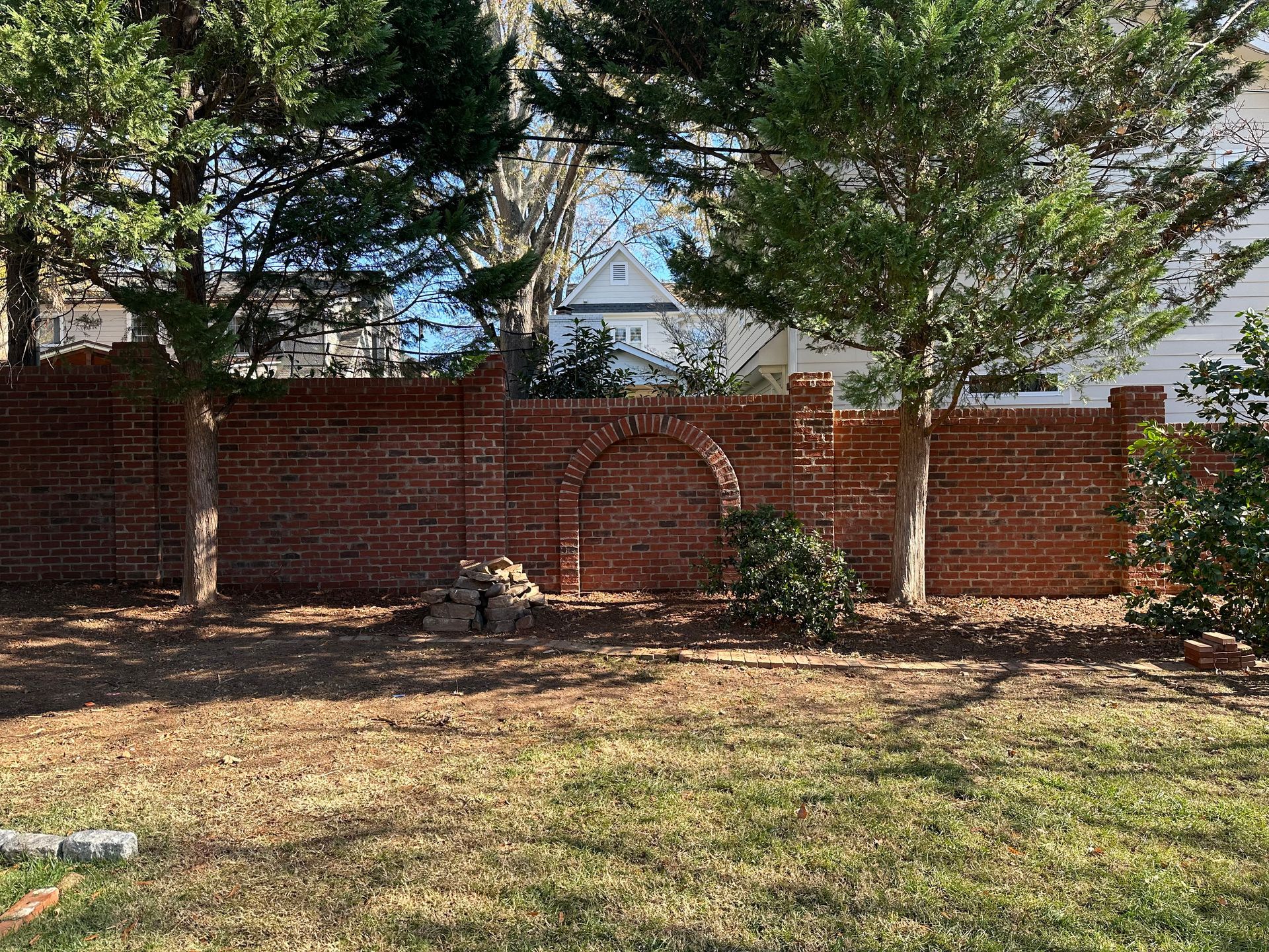 A backyard with a brick wall and trees in the background.