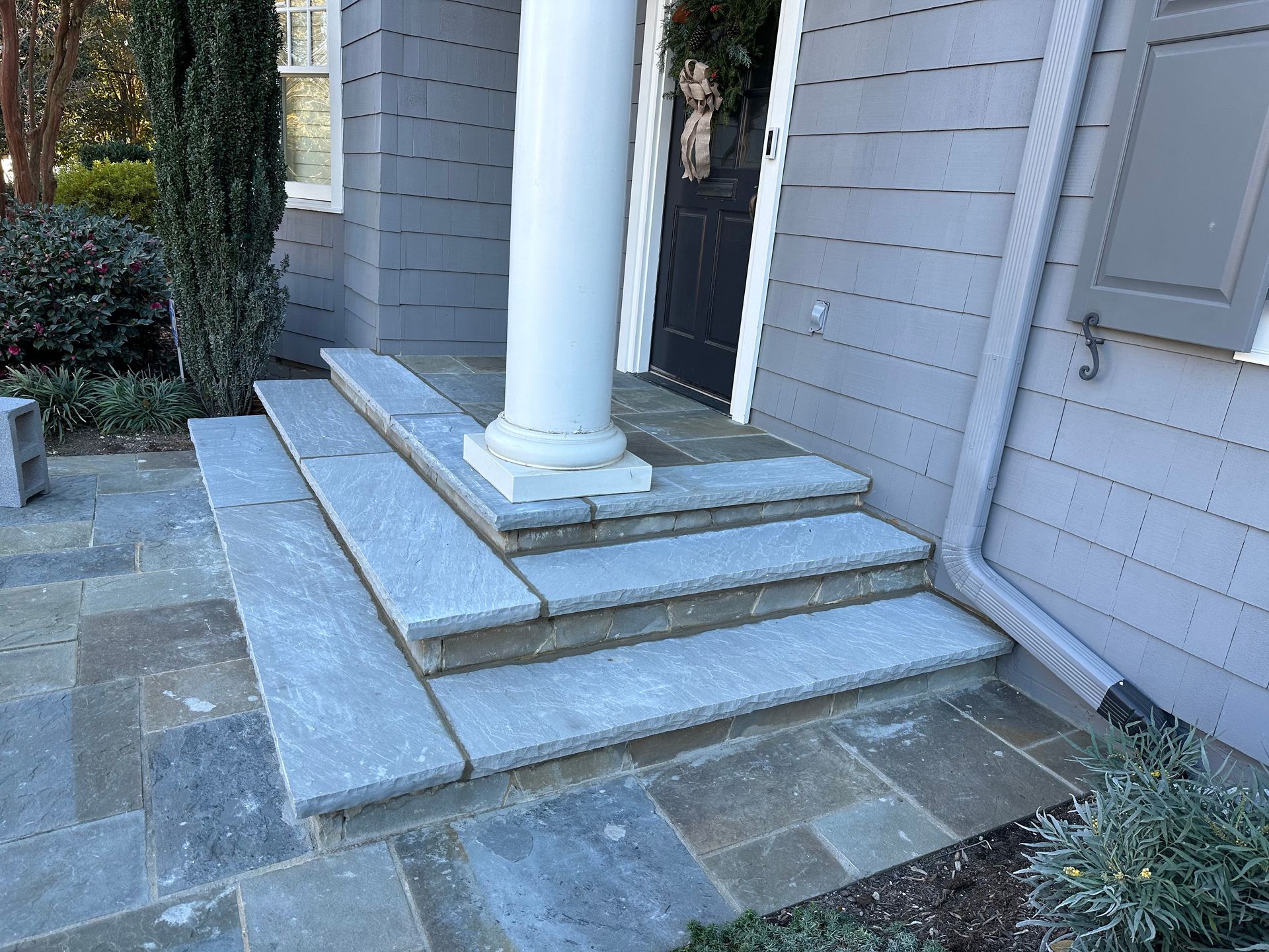 A stone porch with steps and a pillar in front of a house.