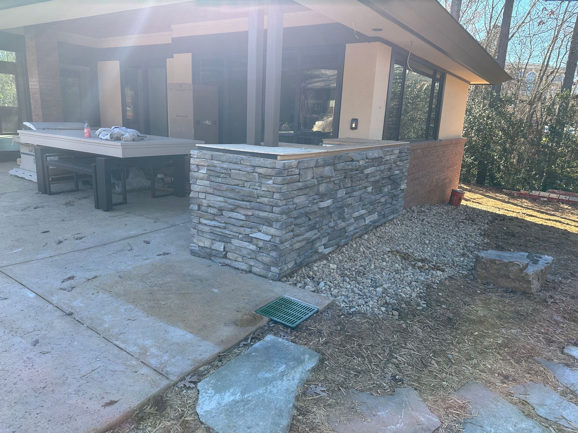 A house with a stone wall and a patio in front of it.