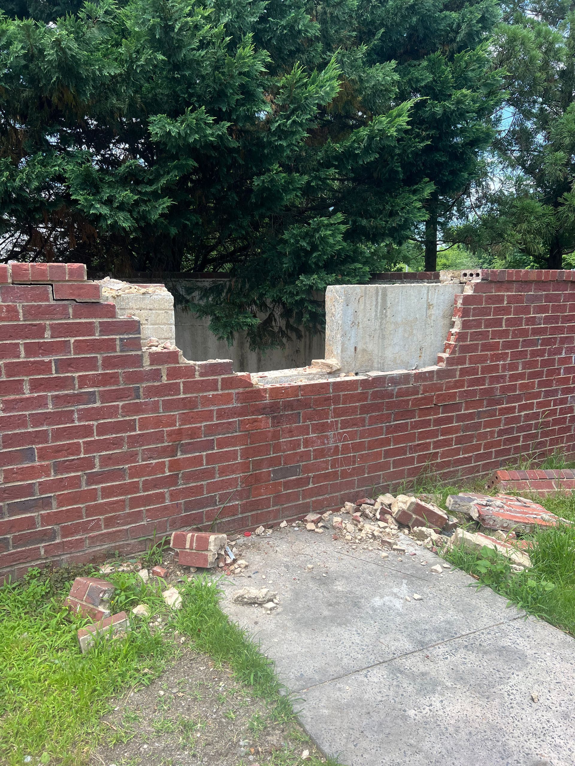 A brick wall with a hole in it is being demolished.