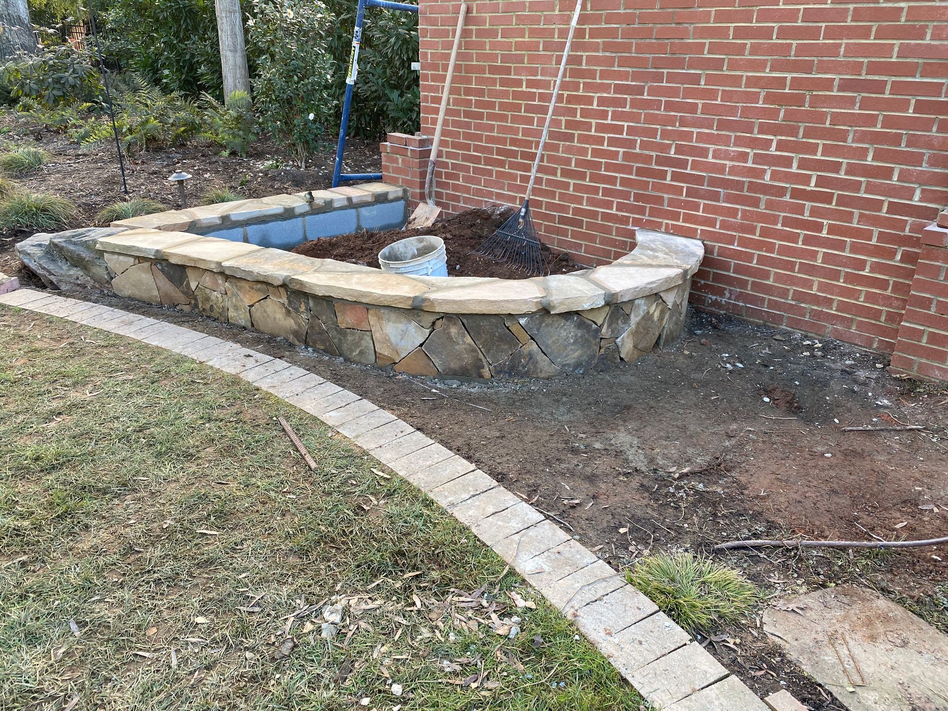 A stone wall is being built in front of a brick wall.