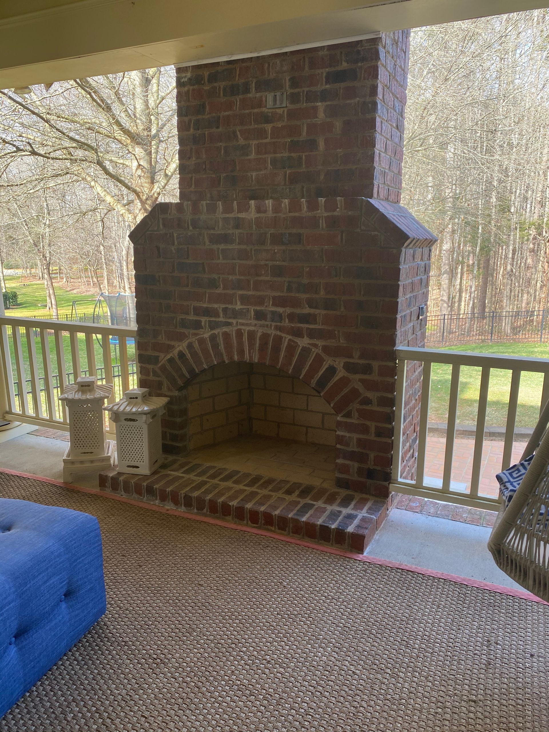 There is a brick fireplace on the porch of a house.