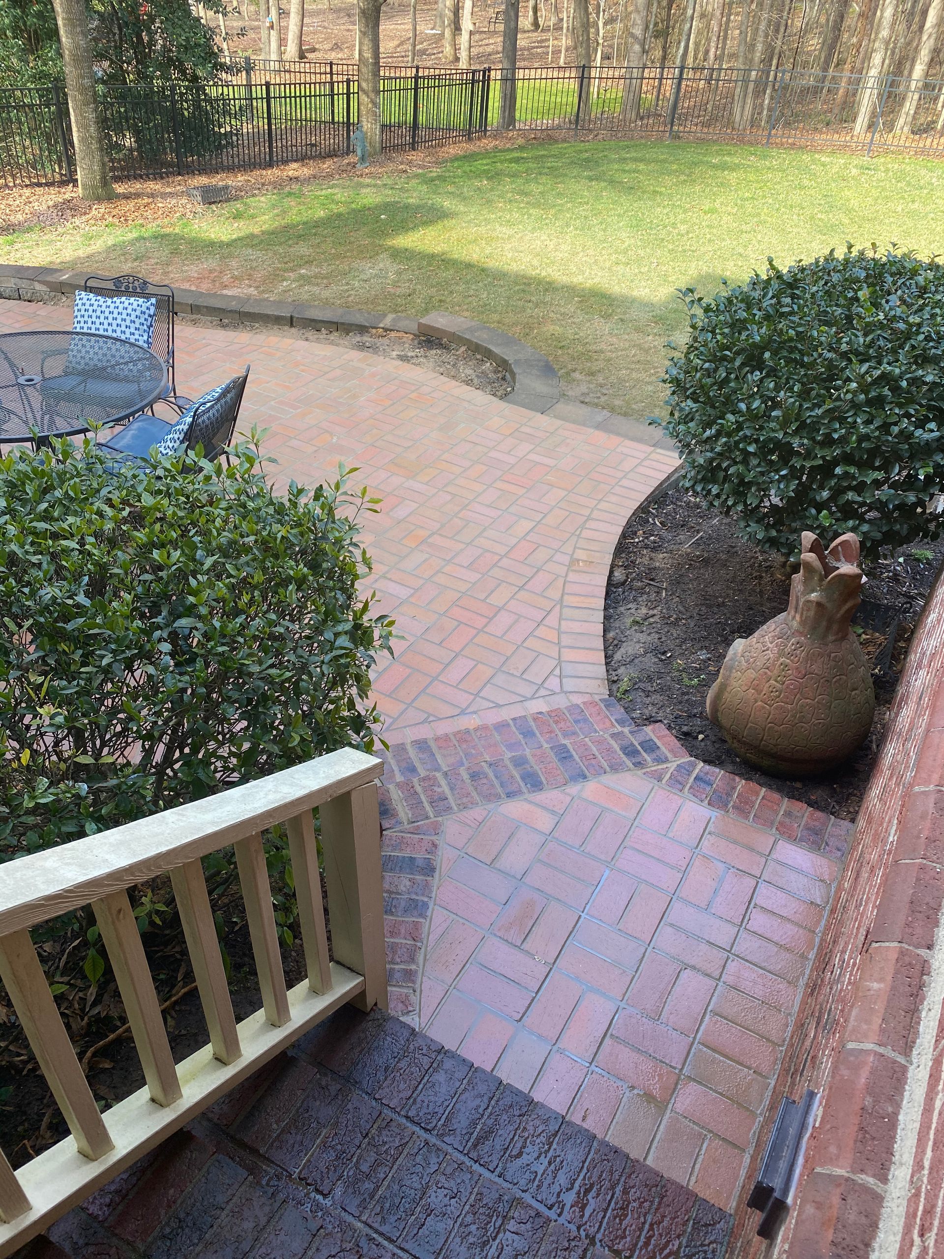 A brick walkway leading to a patio with a table and chairs.