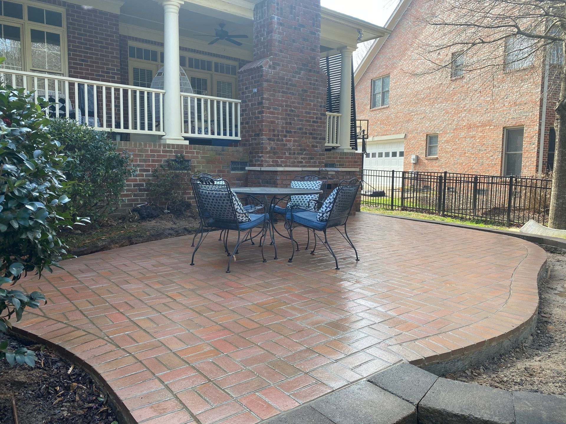 A brick patio with a table and chairs in front of a brick house.