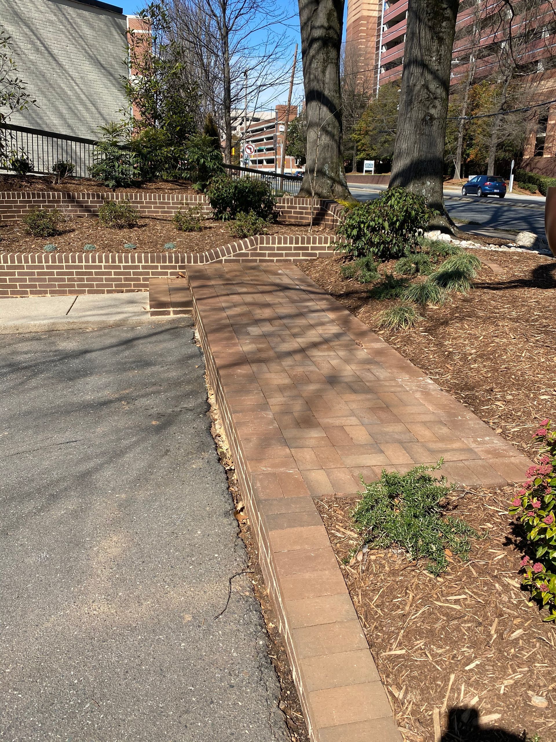 A brick walkway leading to a building in a park.