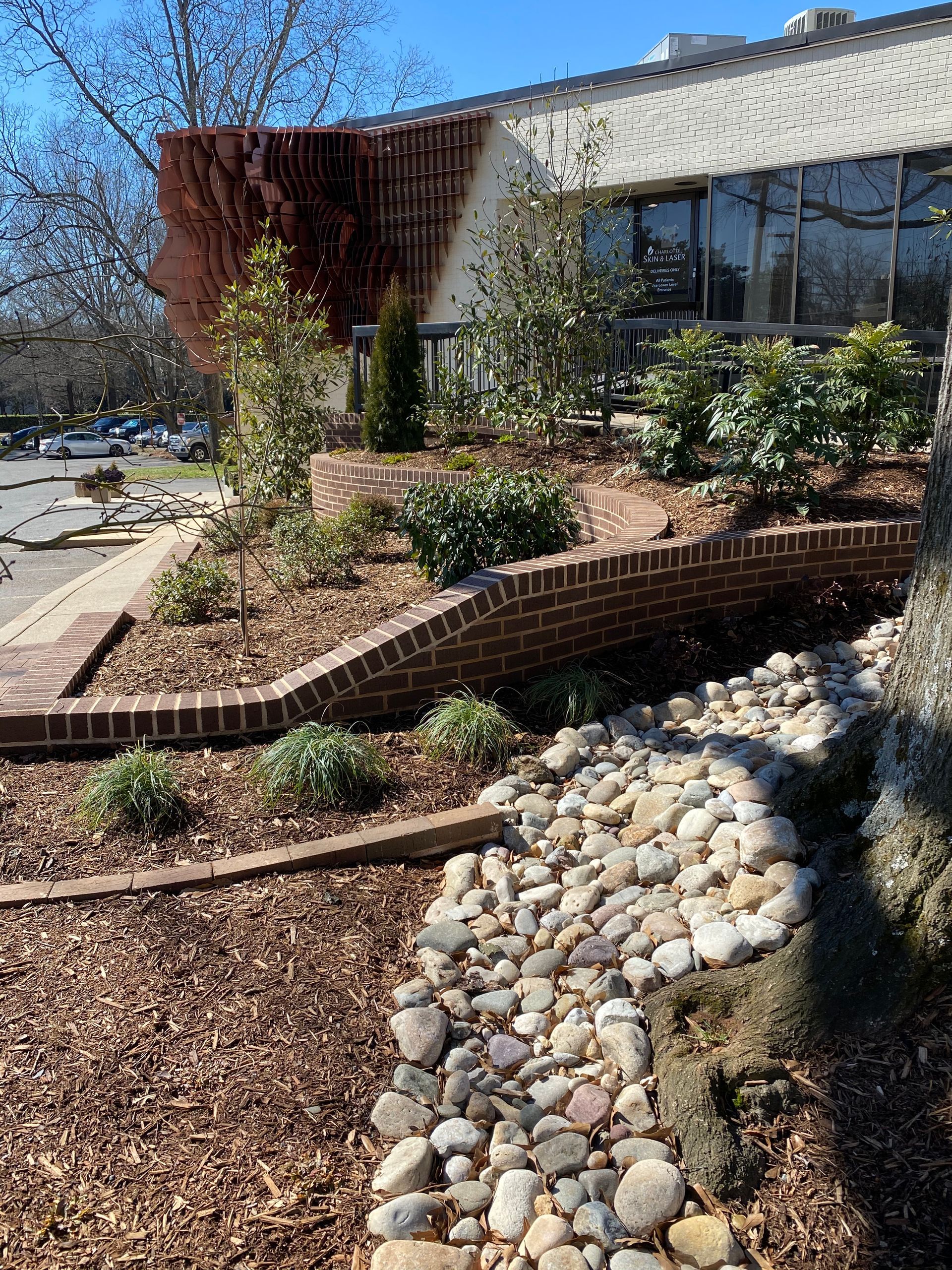 A brick wall with rocks and plants in front of a building.
