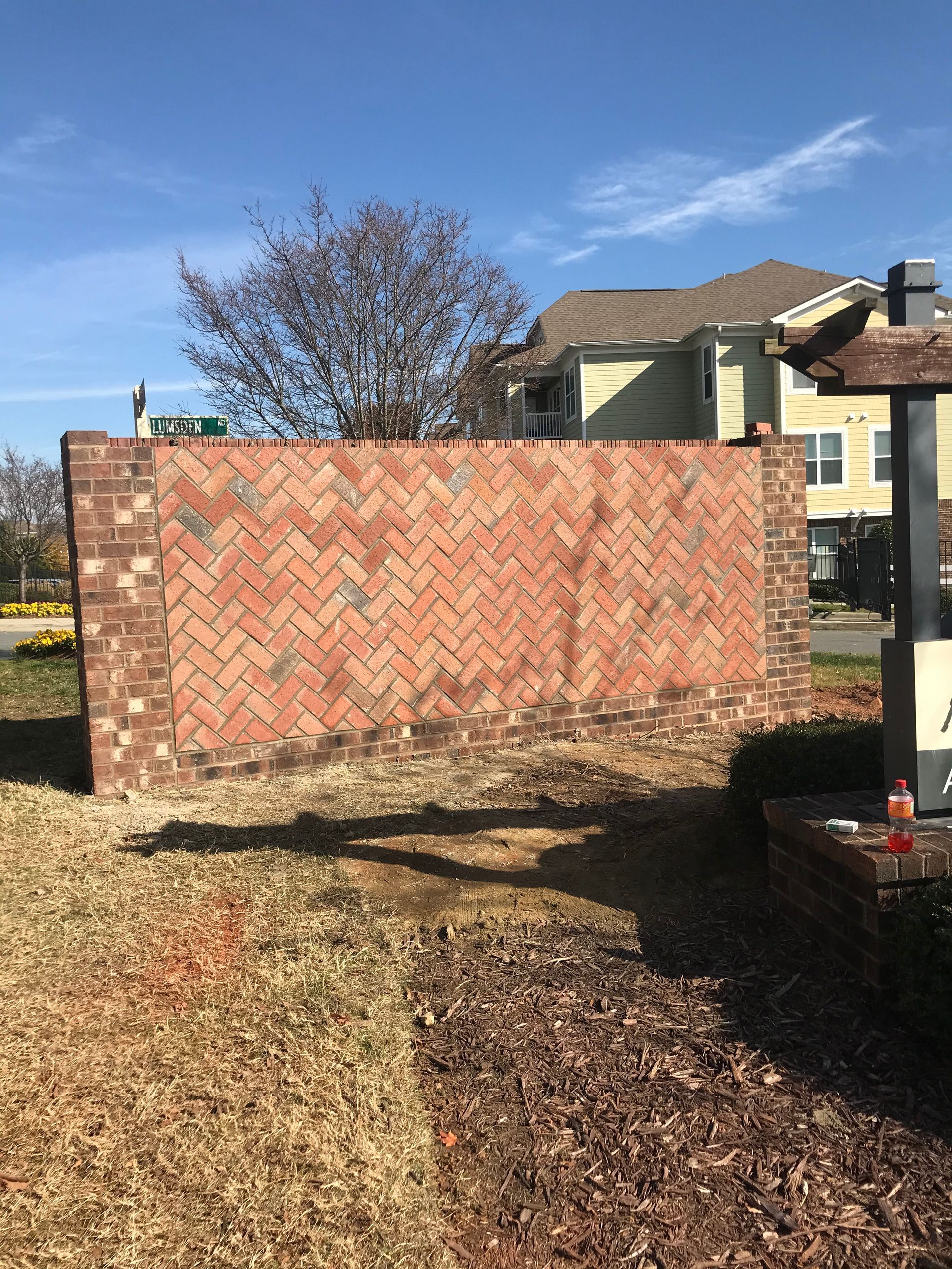 A large brick wall is being built in front of a house.