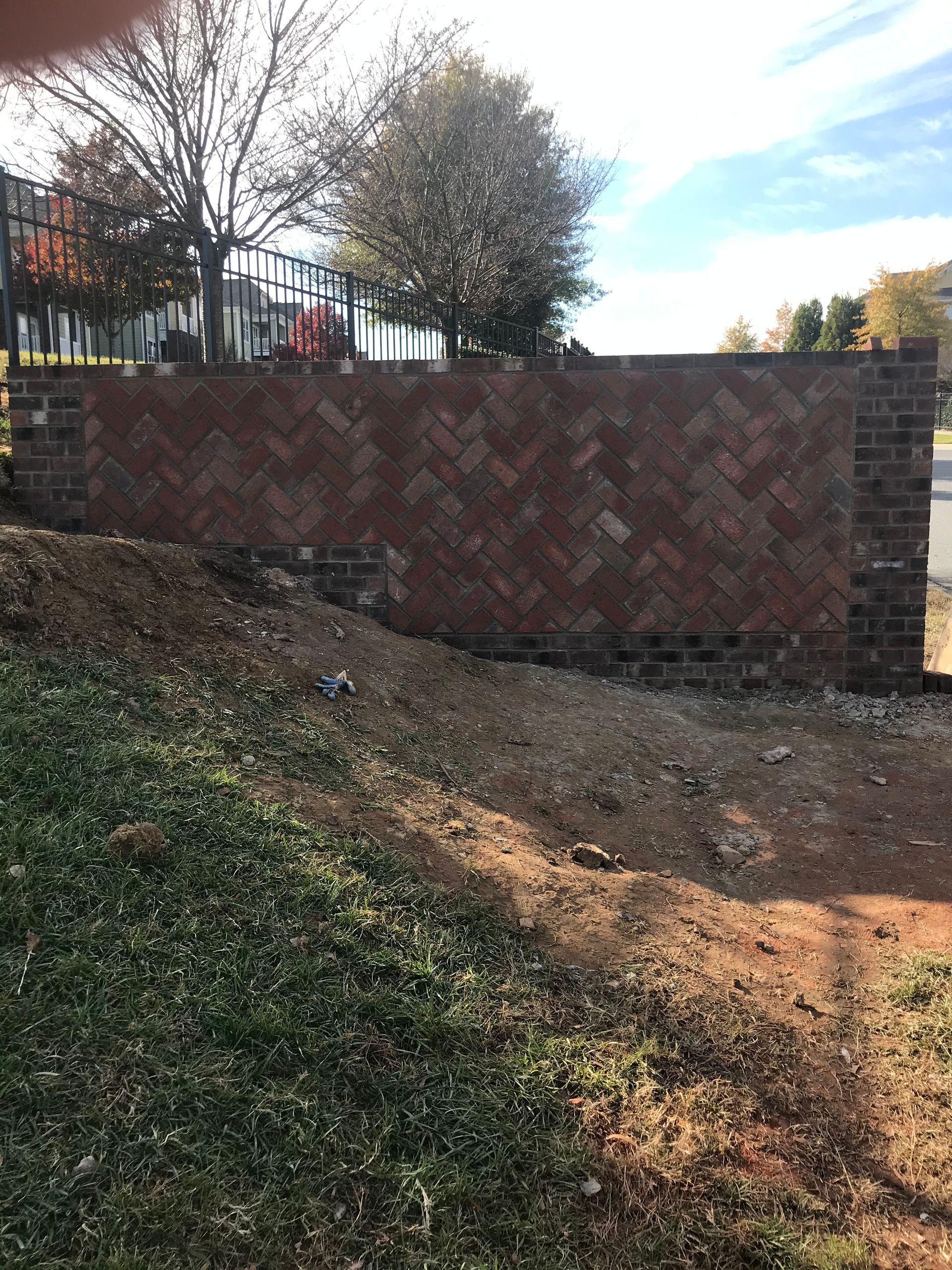 A brick wall is being built next to a grassy field.