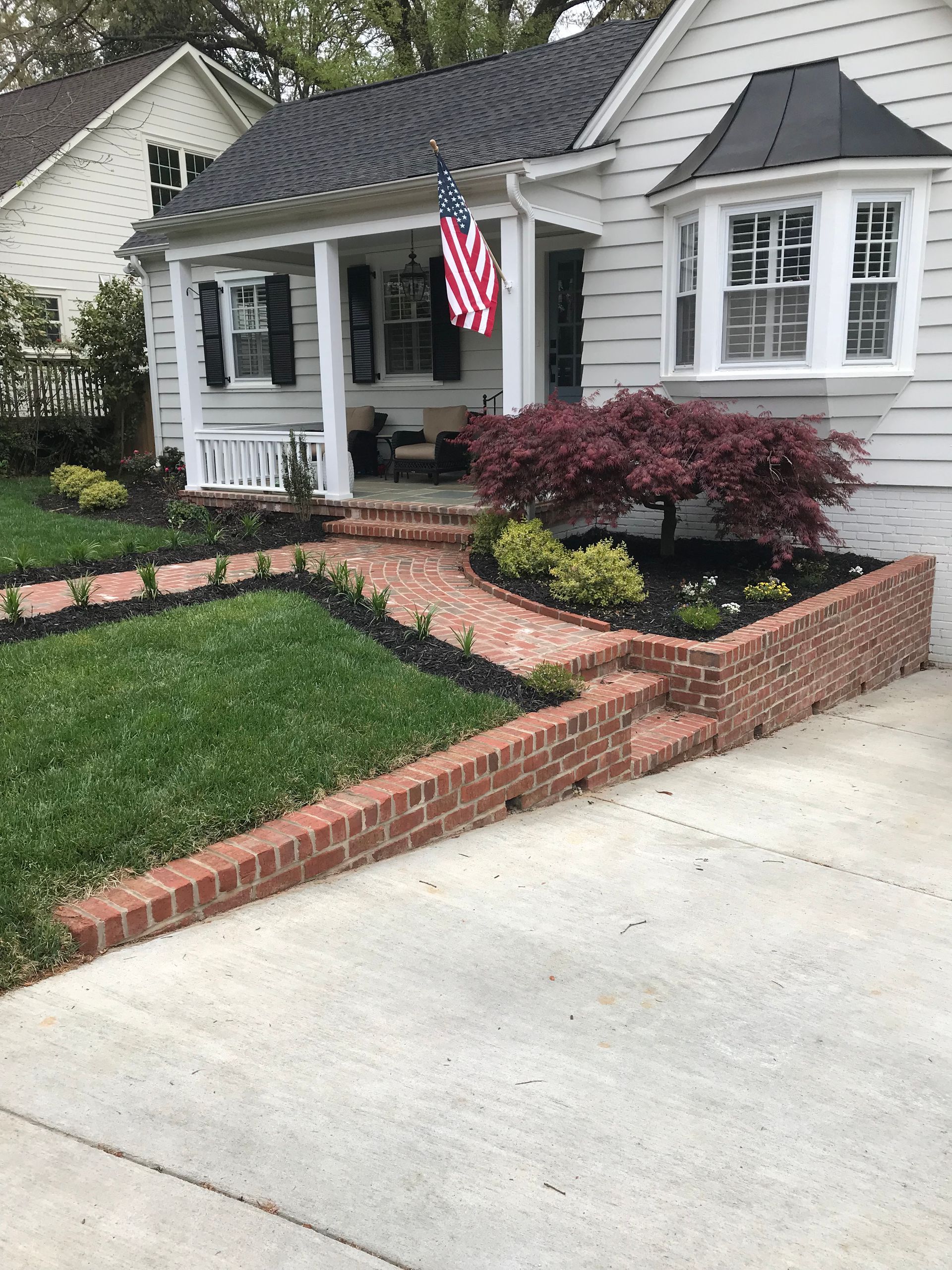 A white house with a brick walkway leading to the front porch.