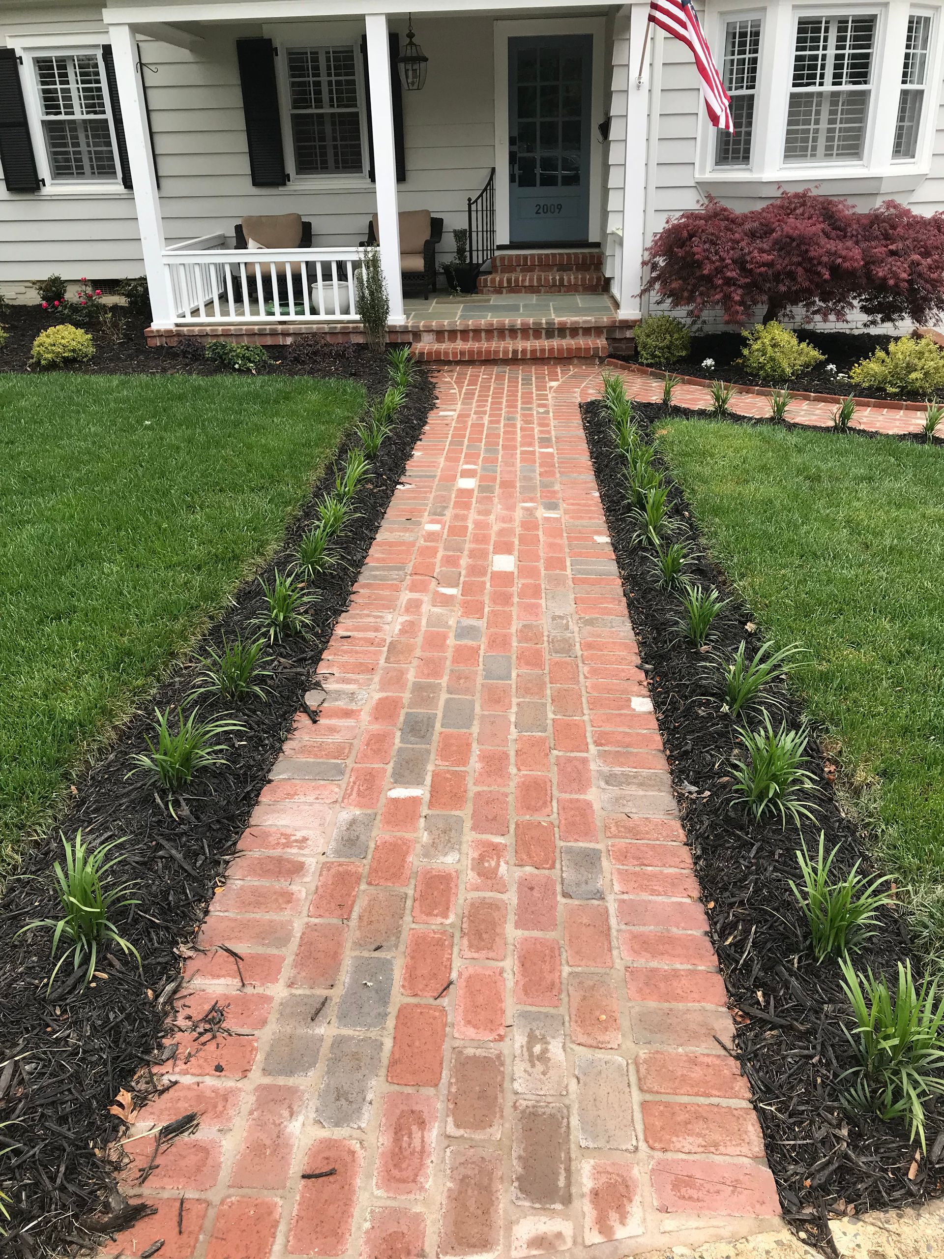 A brick walkway leading to the front of a house.