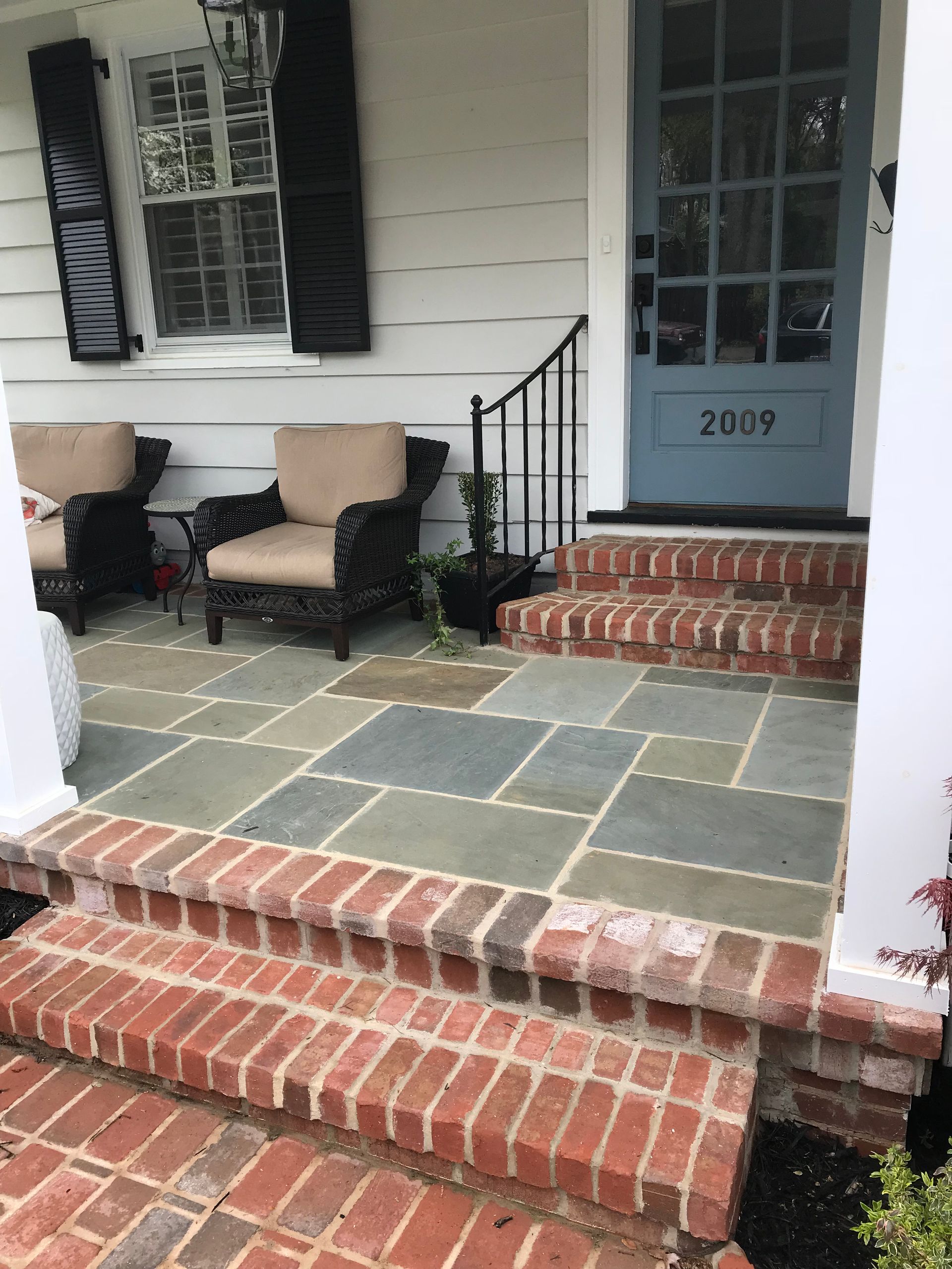 A porch with brick steps and a blue door
