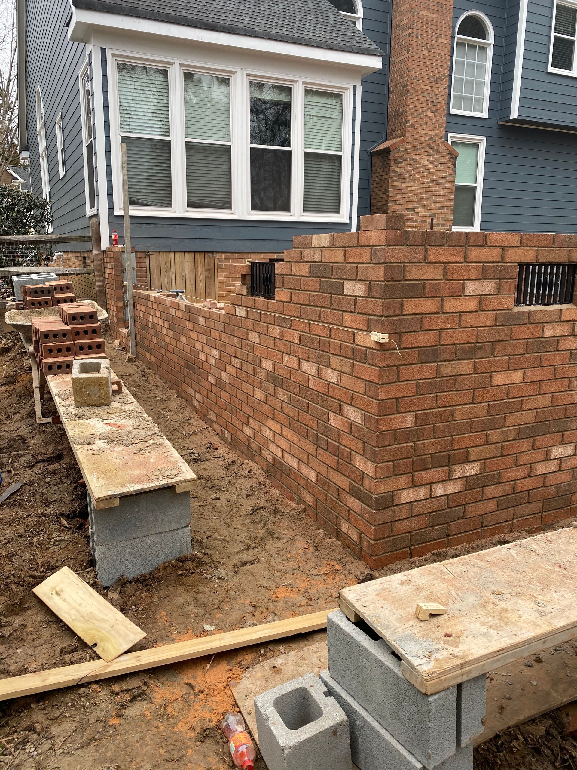 A brick wall is being built in front of a house.