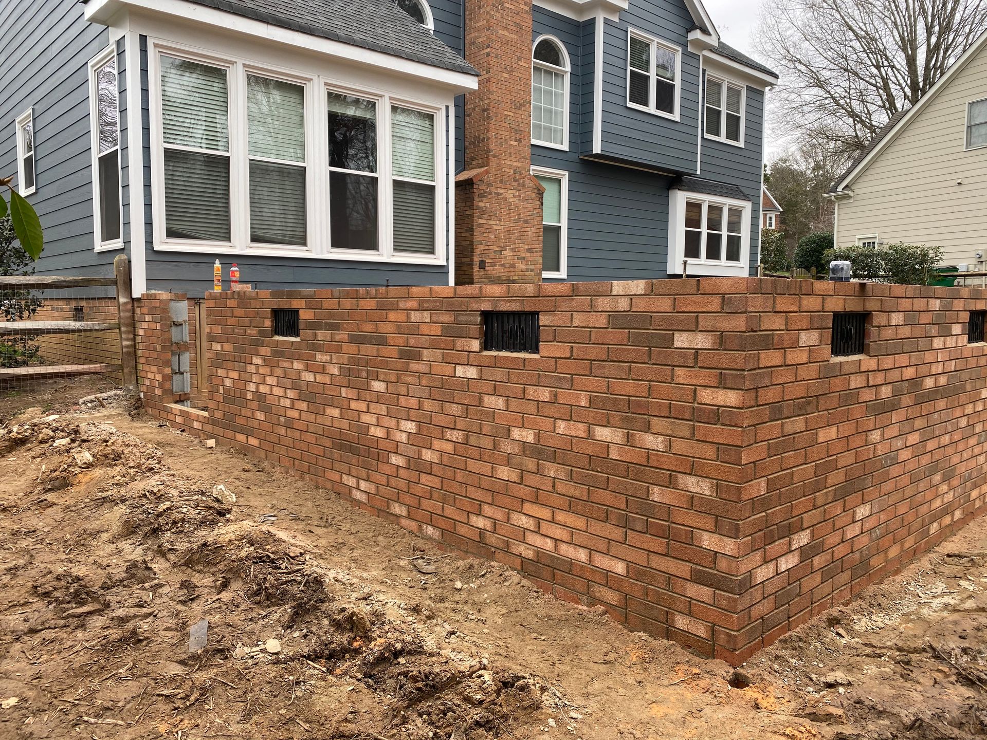A brick wall is being built in front of a house.