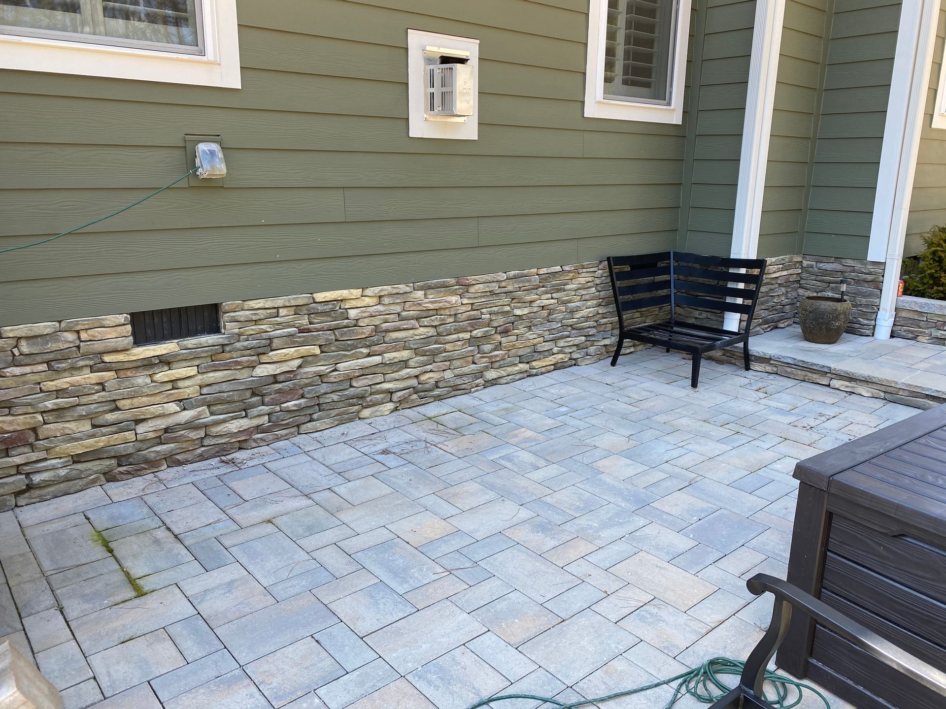 A patio with a bench and a table in front of a house.