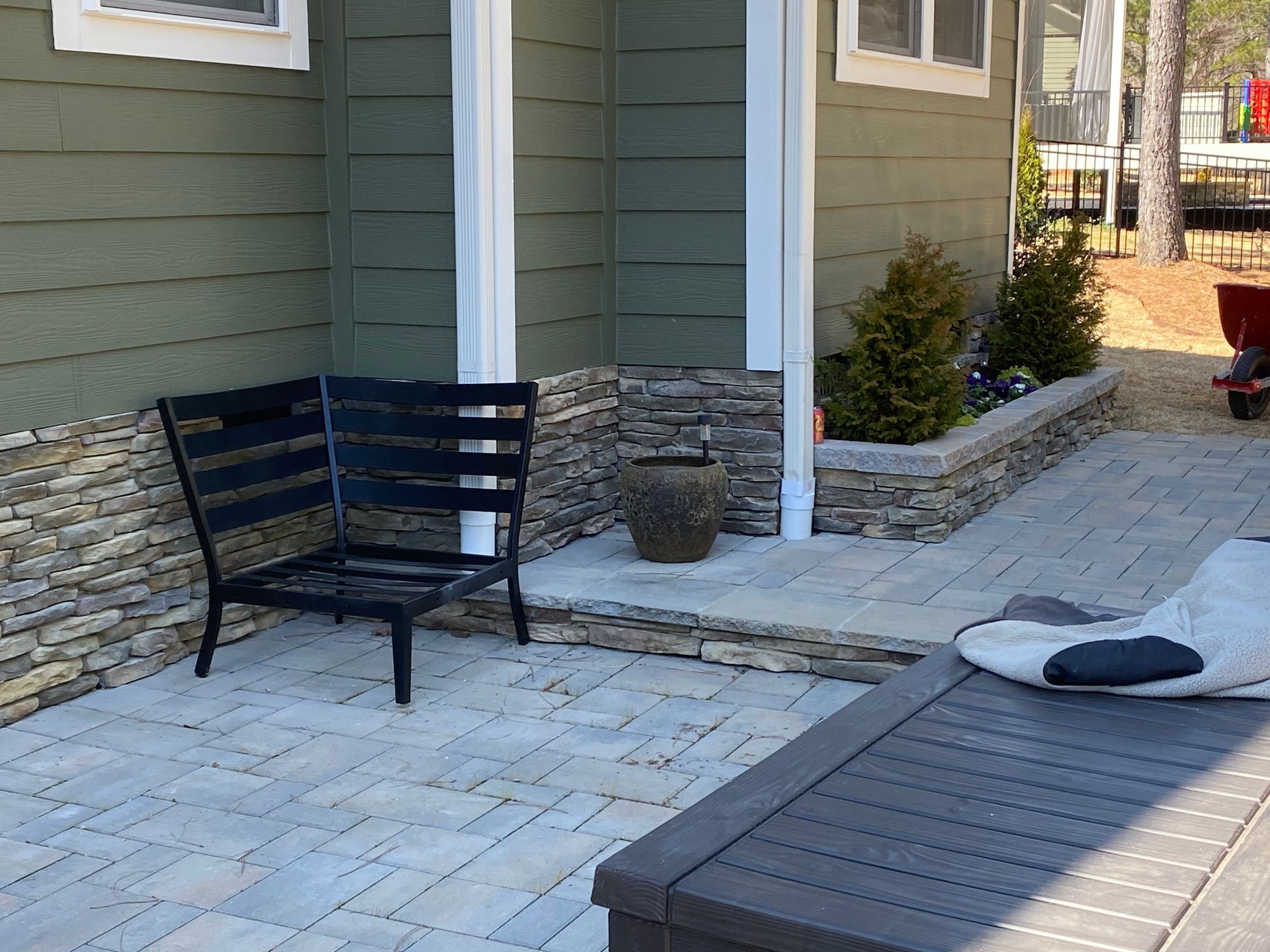 A patio with a bench and a table in front of a house