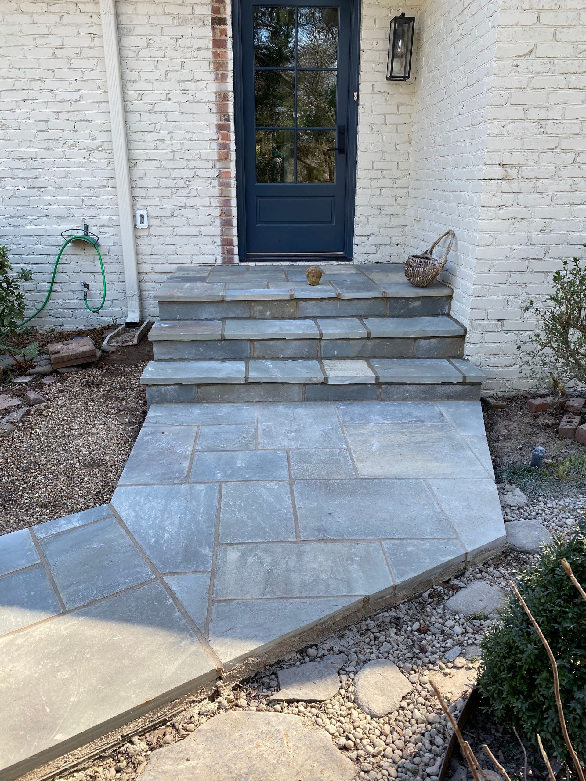 A stone walkway leading to the front door of a white brick house.