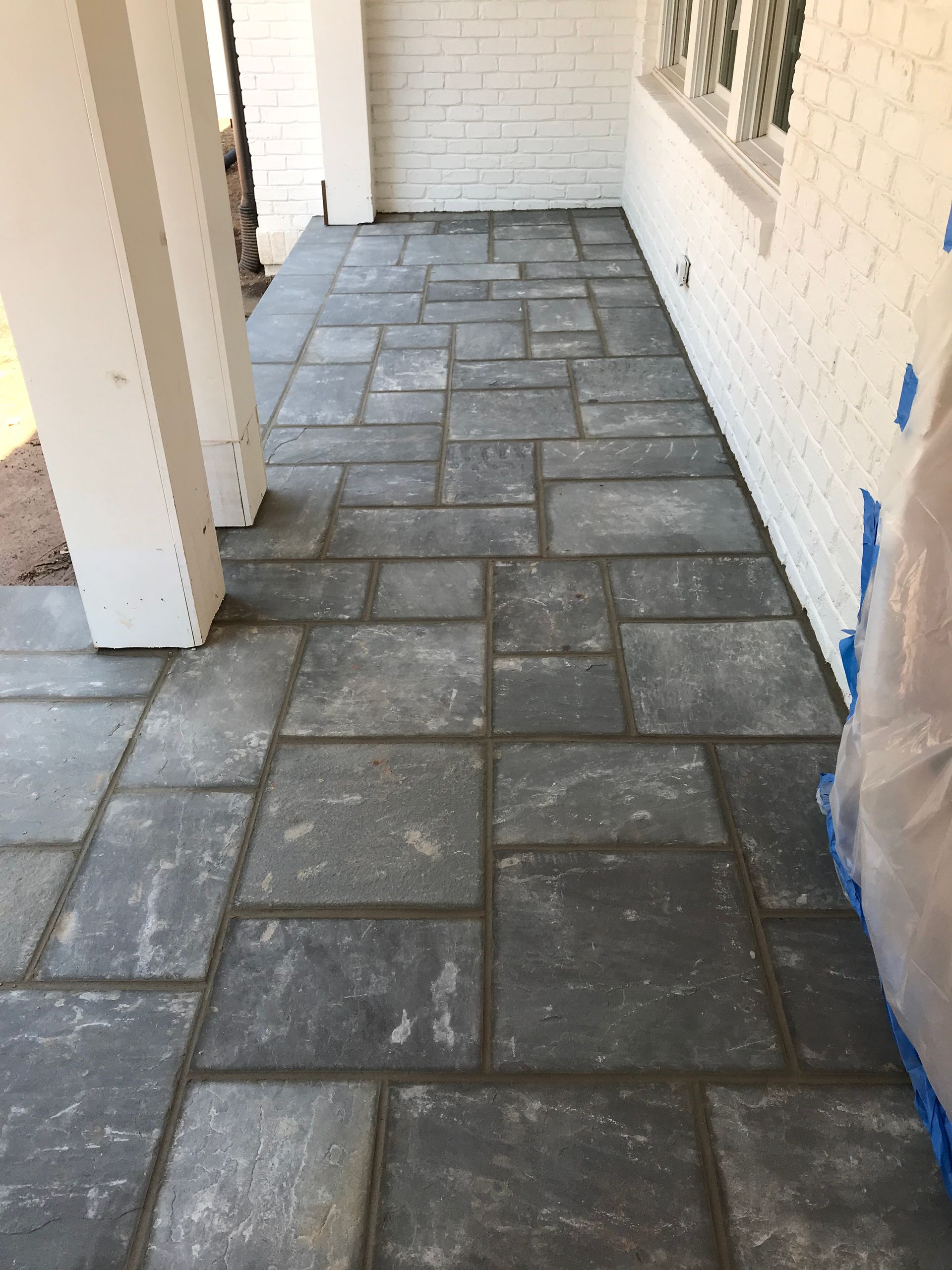A brick walkway with a white brick wall in the background.