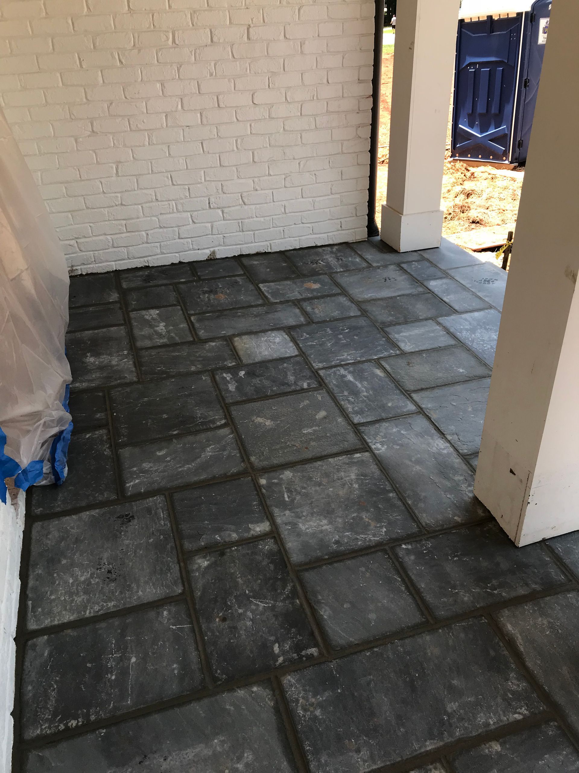 A brick wall with a black tile floor in front of it.