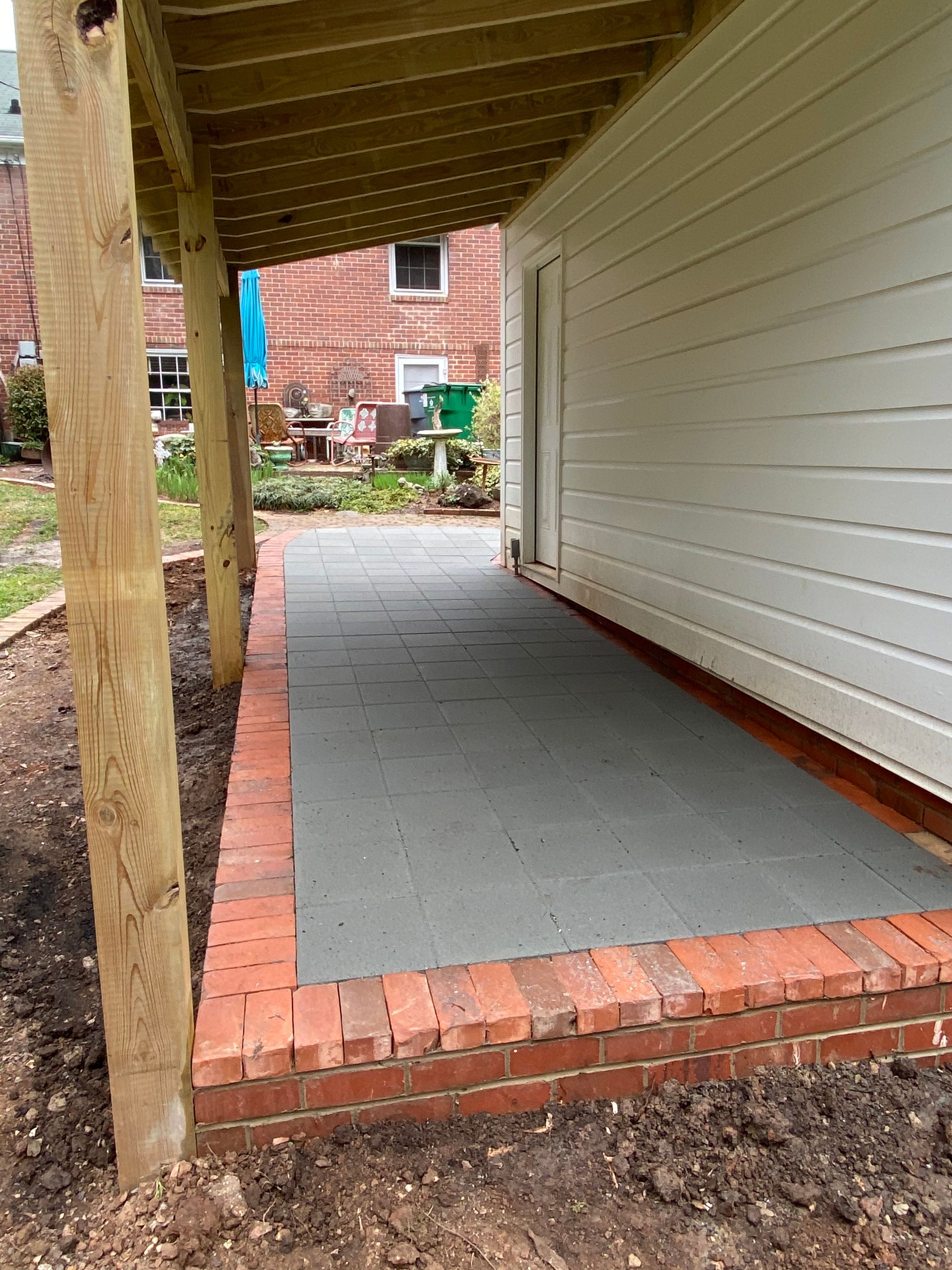 A brick walkway leading to a house with a wooden deck.