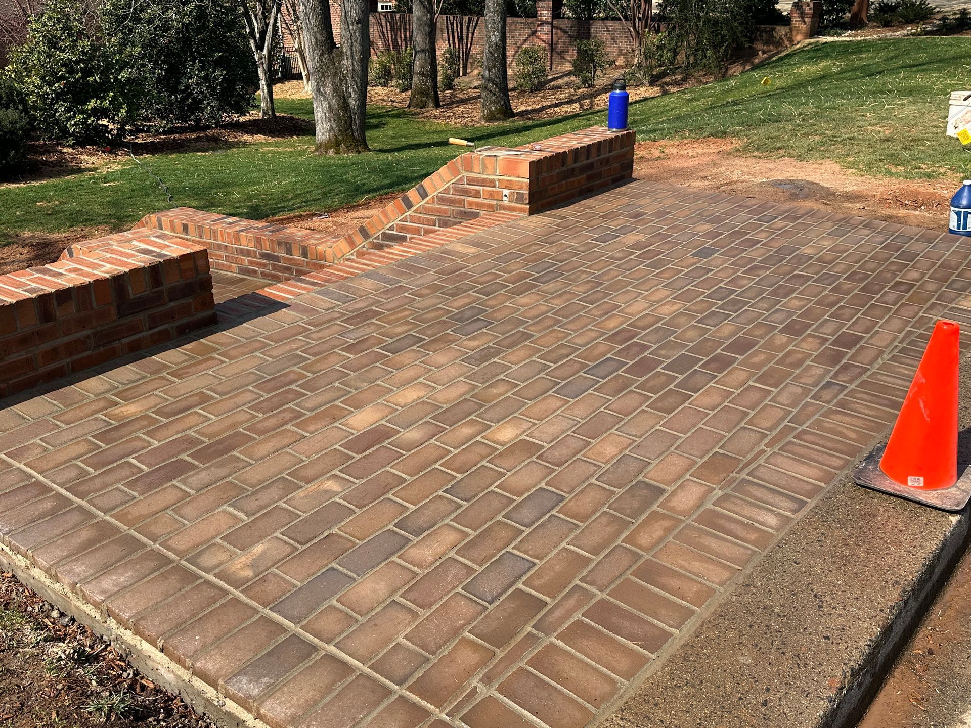 A brick walkway with a cone on the side of it.