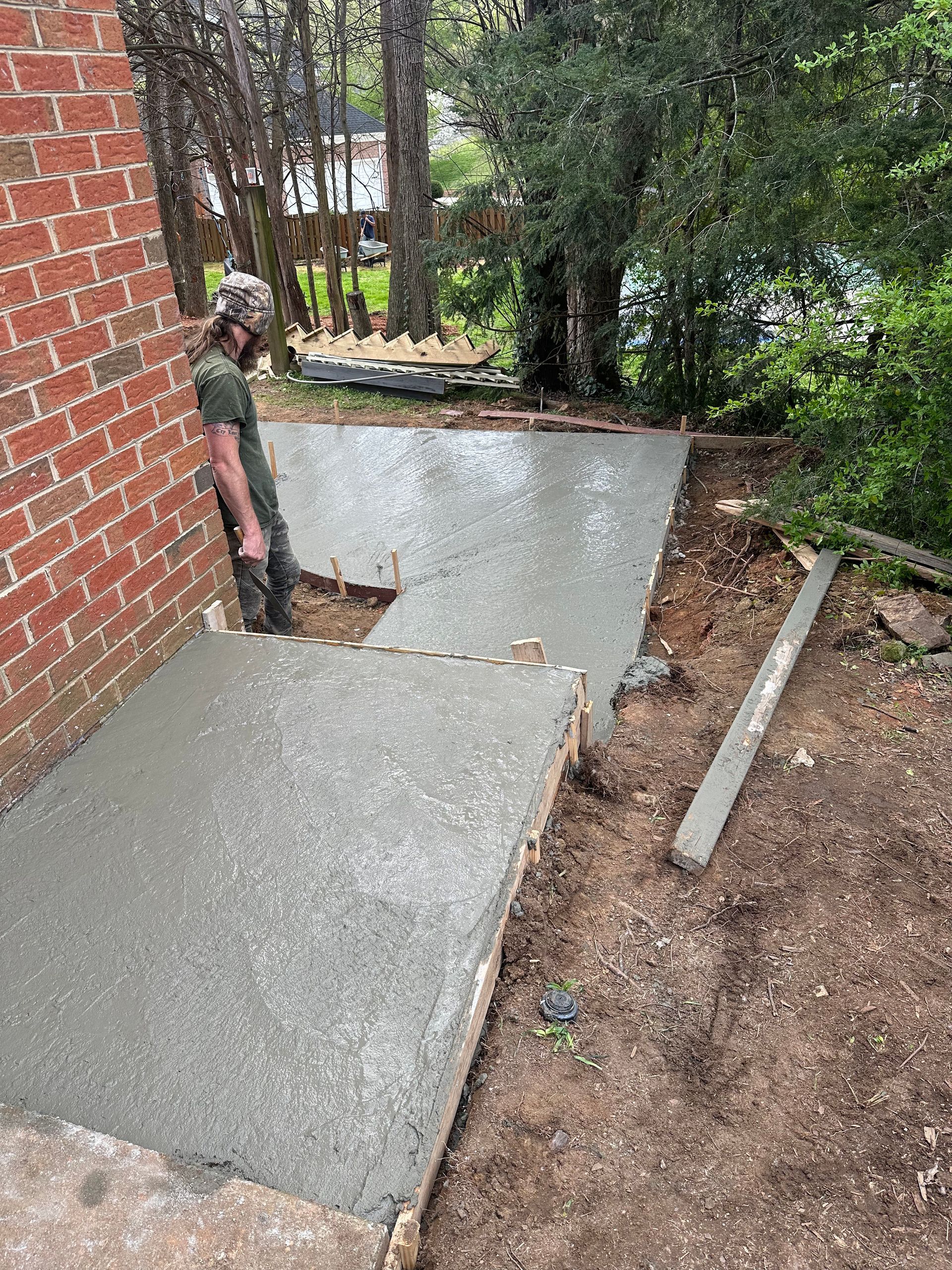 A man is standing on a concrete walkway next to a brick wall.
