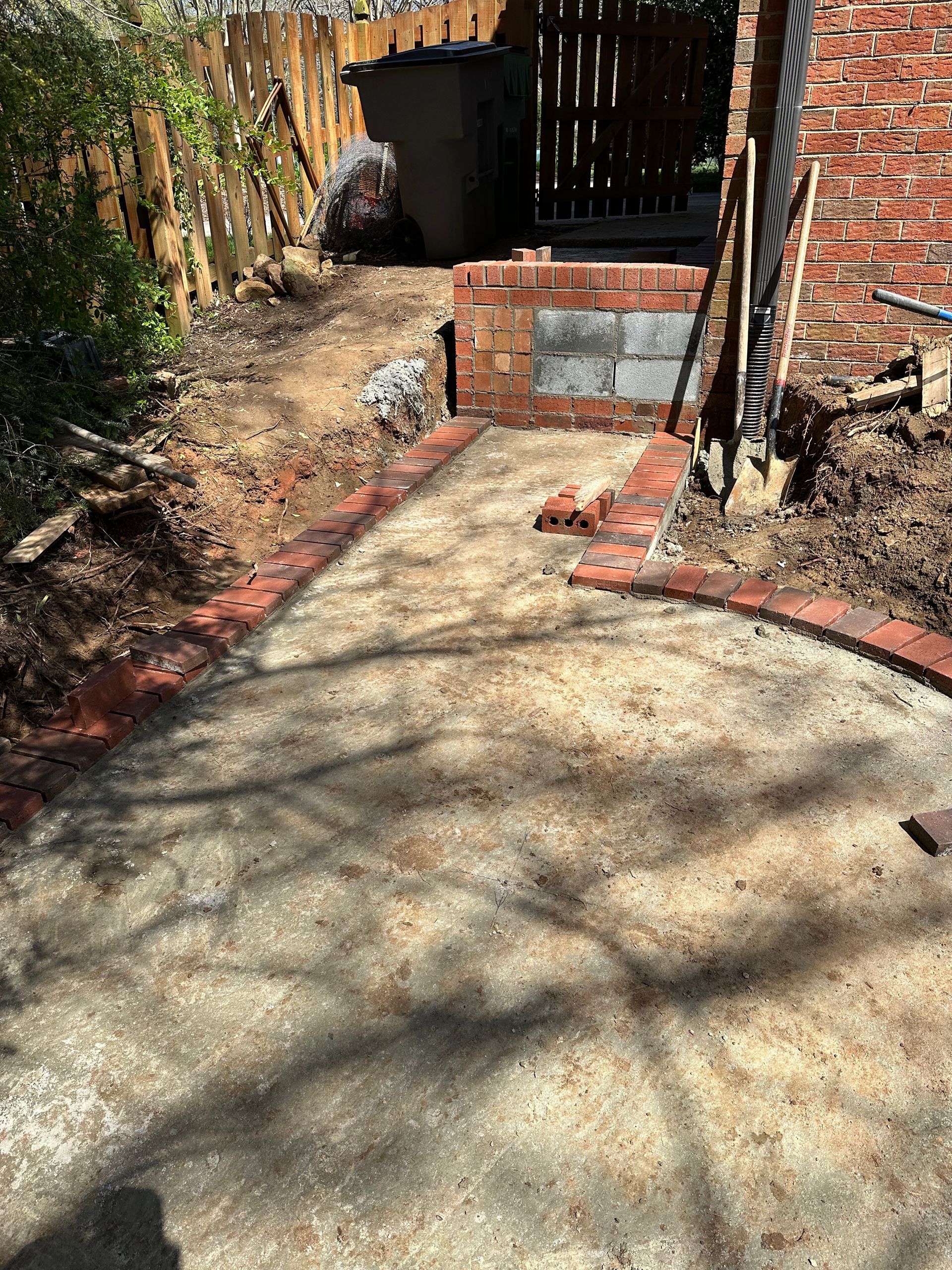 A brick walkway is being built in the backyard of a house.