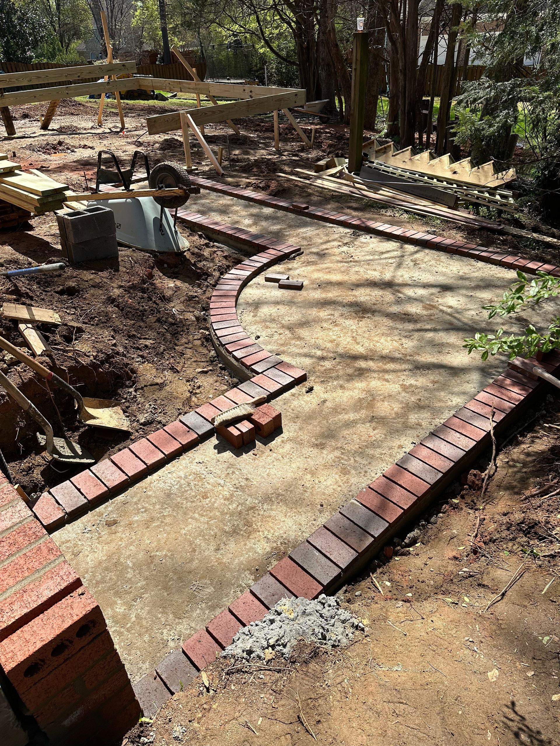 A brick walkway is being built in the middle of a dirt field.