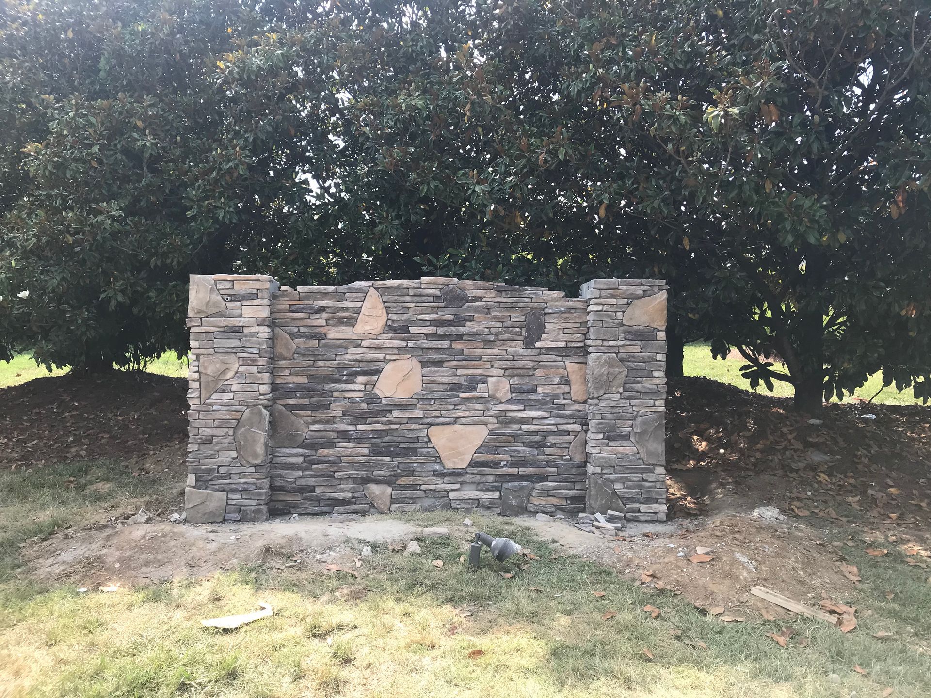 A stone wall in the middle of a field with trees in the background