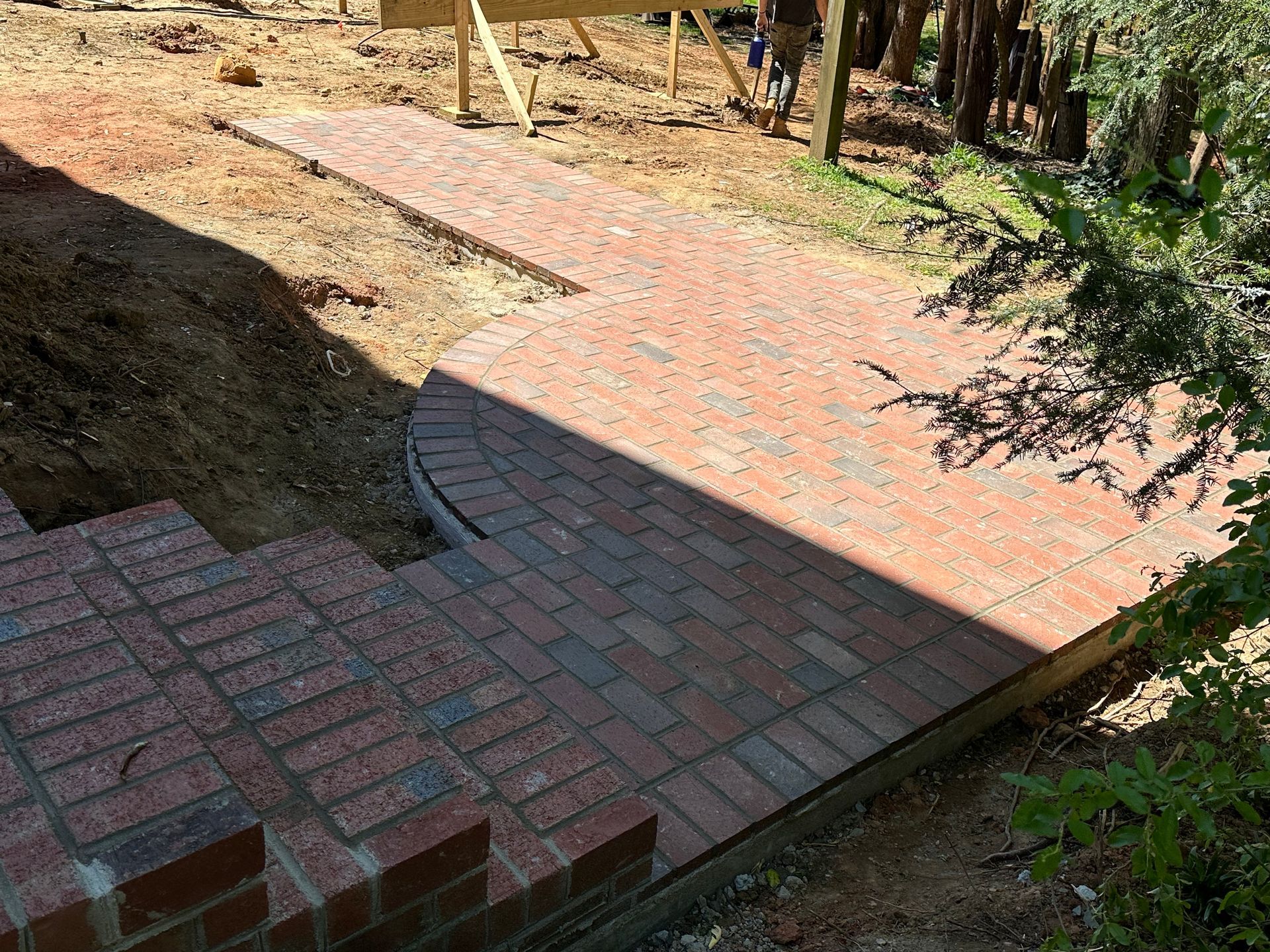 A brick walkway is being built in a backyard.