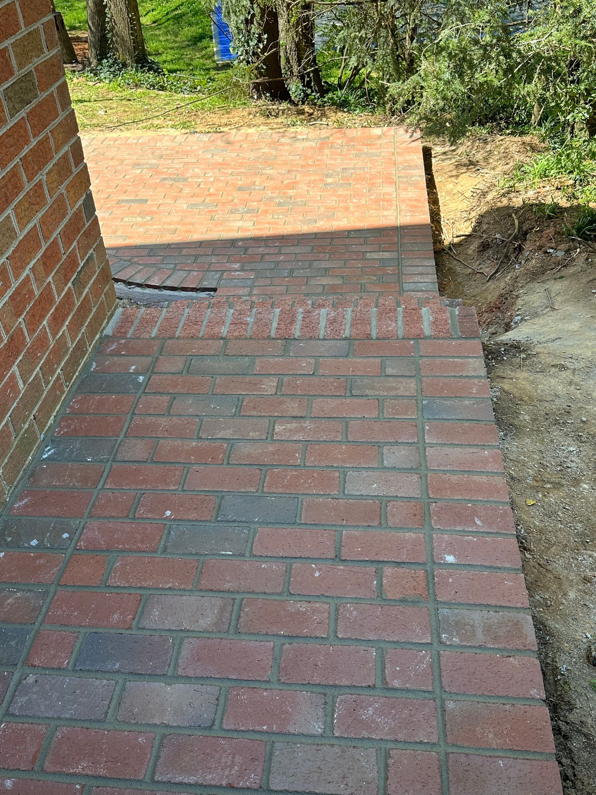 A brick walkway is being built next to a brick wall.