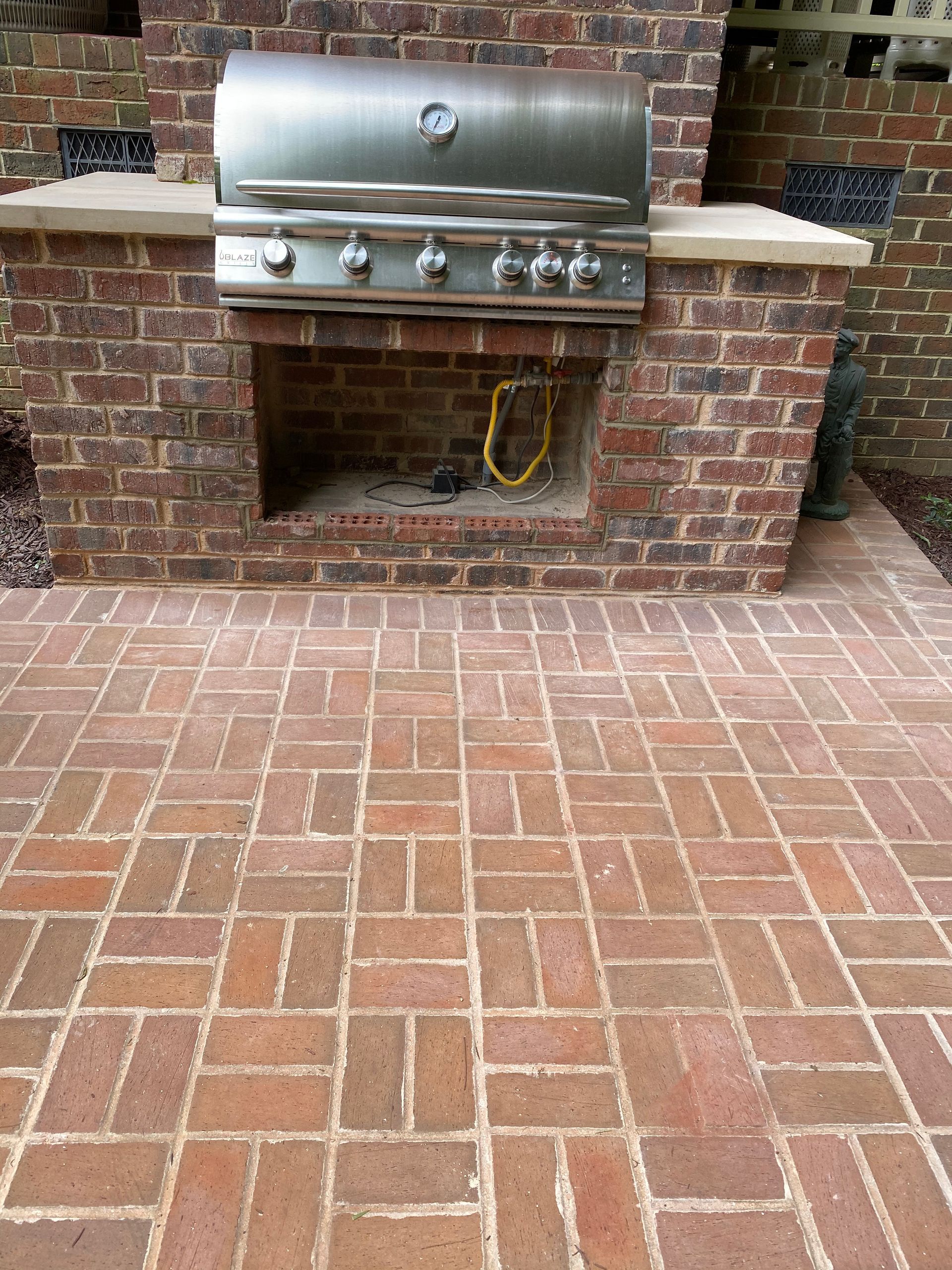A grill is built into a brick fireplace.