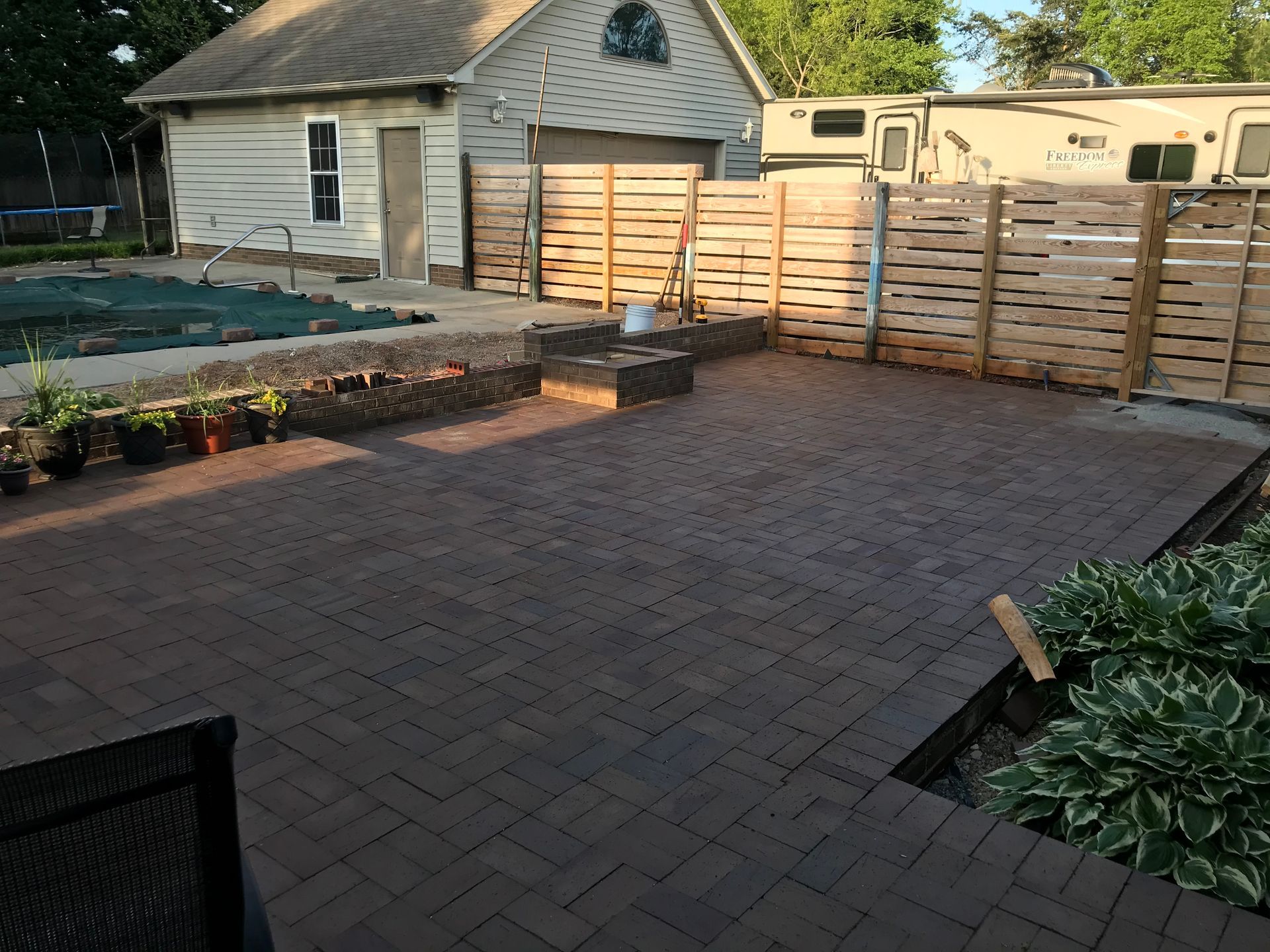 A patio with a wooden fence and a house in the background.