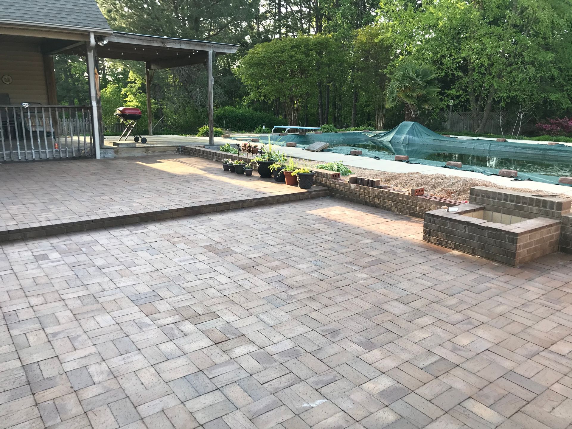 A brick patio with a swimming pool in the background.