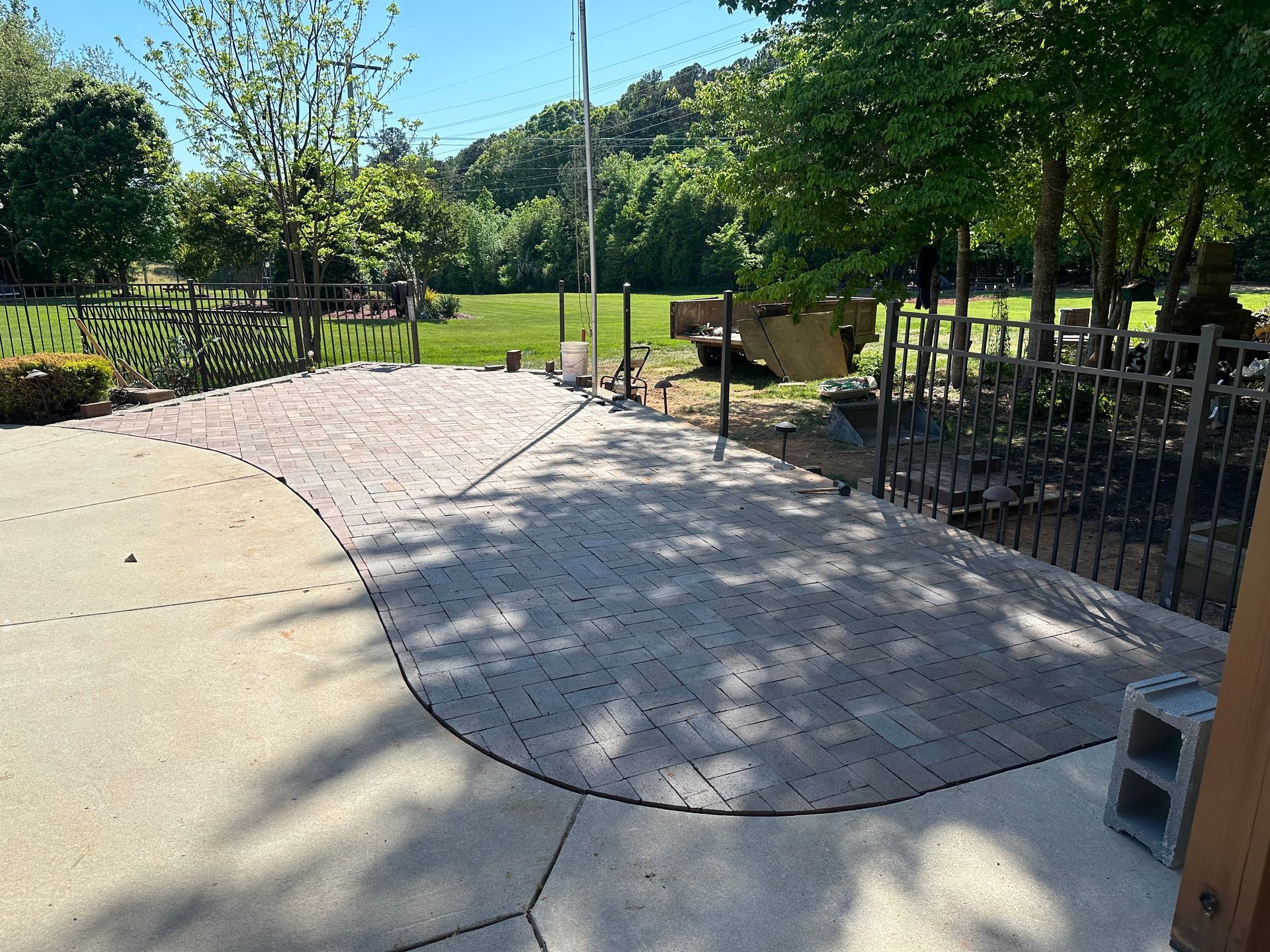 A patio with a fence and trees in the background
