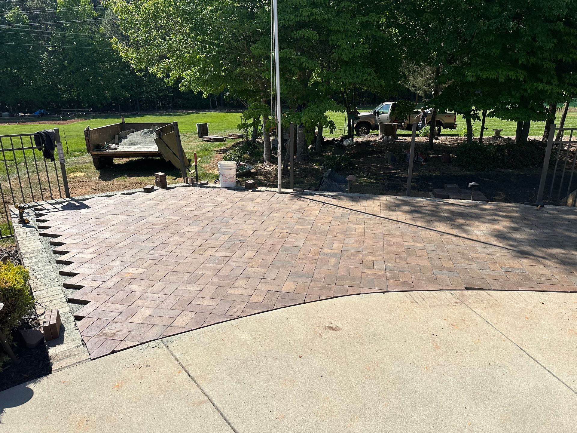 A brick driveway is being built in a park with trees in the background.