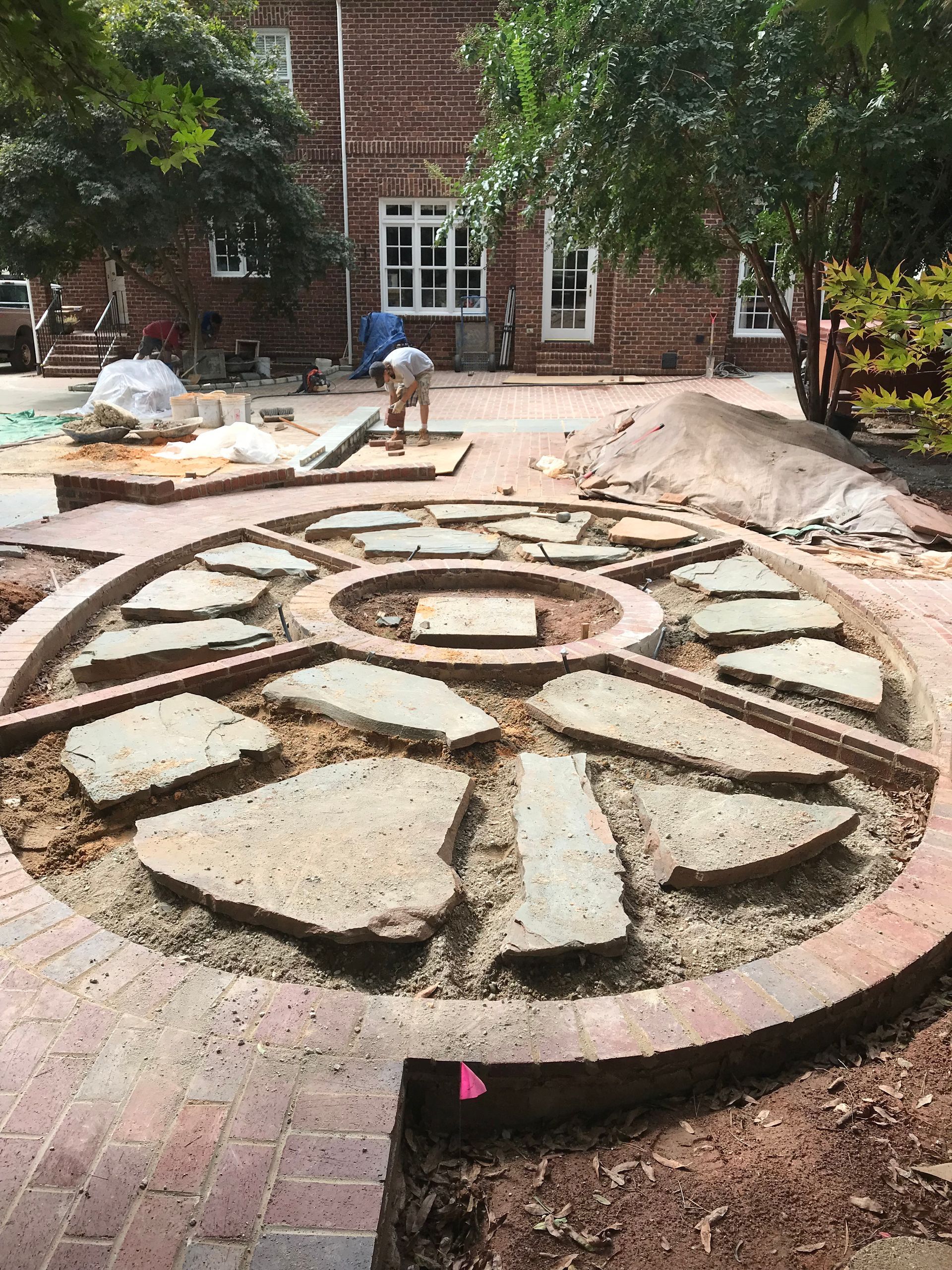 A circular stone walkway is being built in front of a brick building.