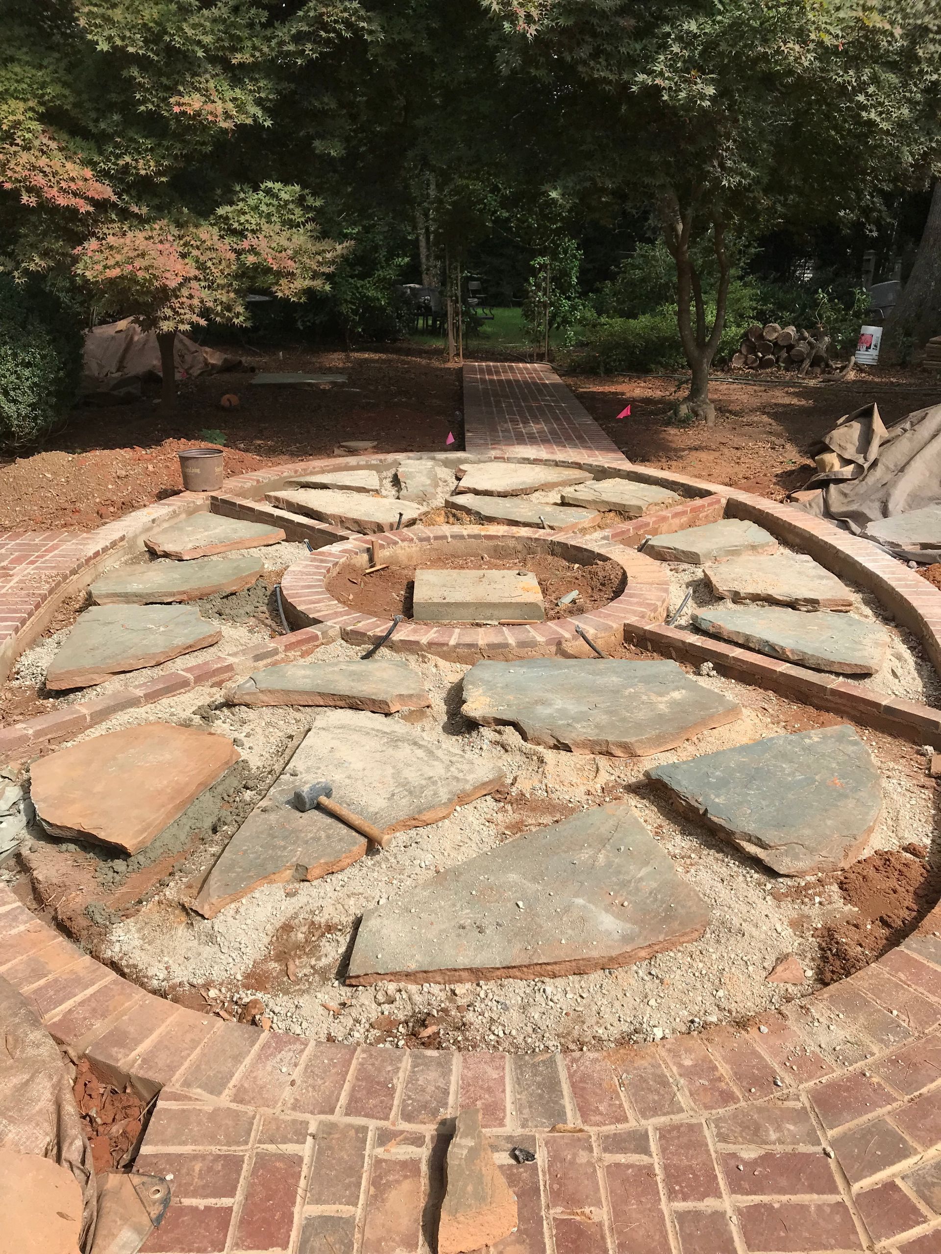 A circular stone walkway with a fire pit in the middle of it.