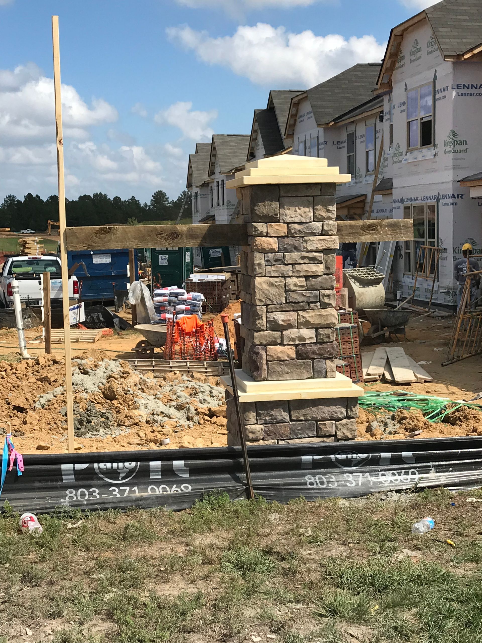 A brick column is sitting in the middle of a construction site.
