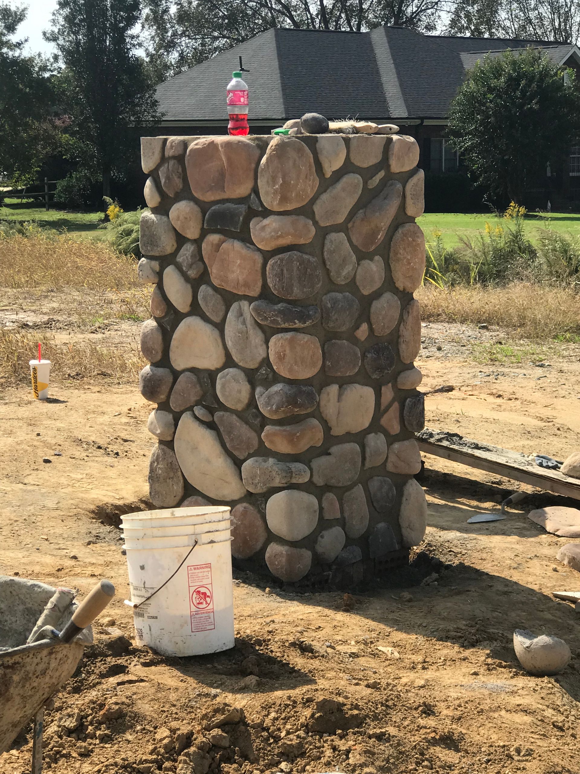 A stone wall with a bucket in front of it